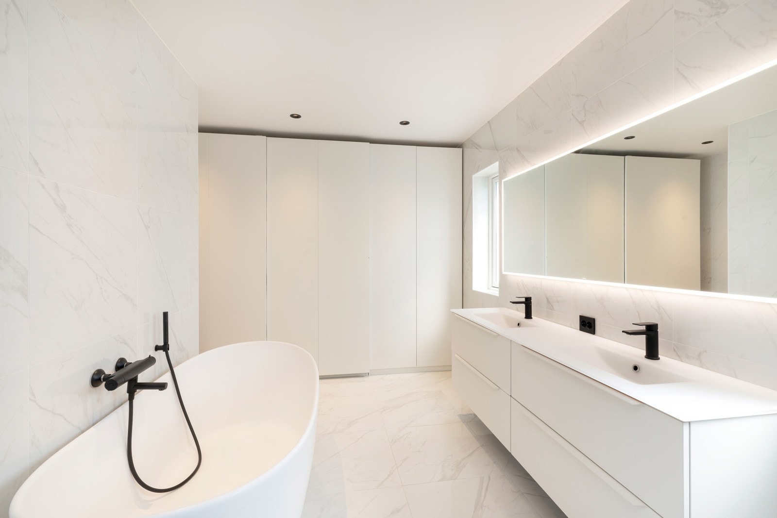 Badet er blant annet badekar, dobbel vask, vegghengt toalett, garderobe og dobbel dusj Galleribilde