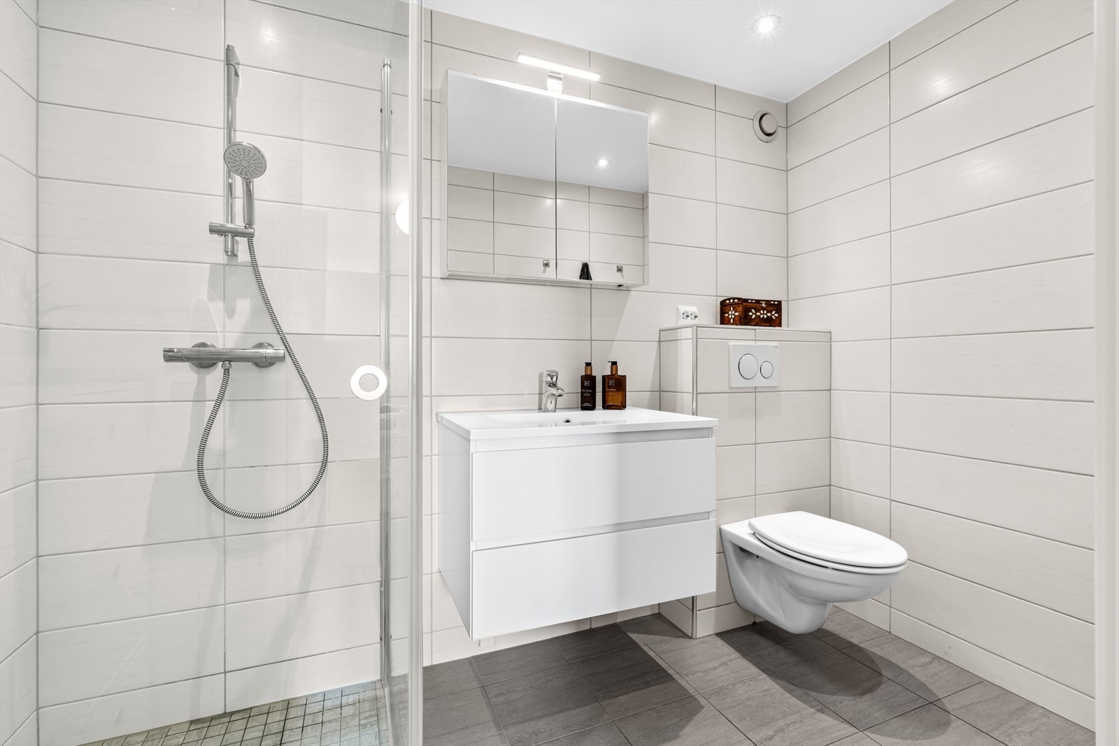 Delikat og moderne bad med stilrene, flislagte overflater i lyse og tidløse farger. Badet ble renovert i samme periode (2016) som det andre baderommet og har praktisk adkomst fra hovedsoverommet. Galleribilde