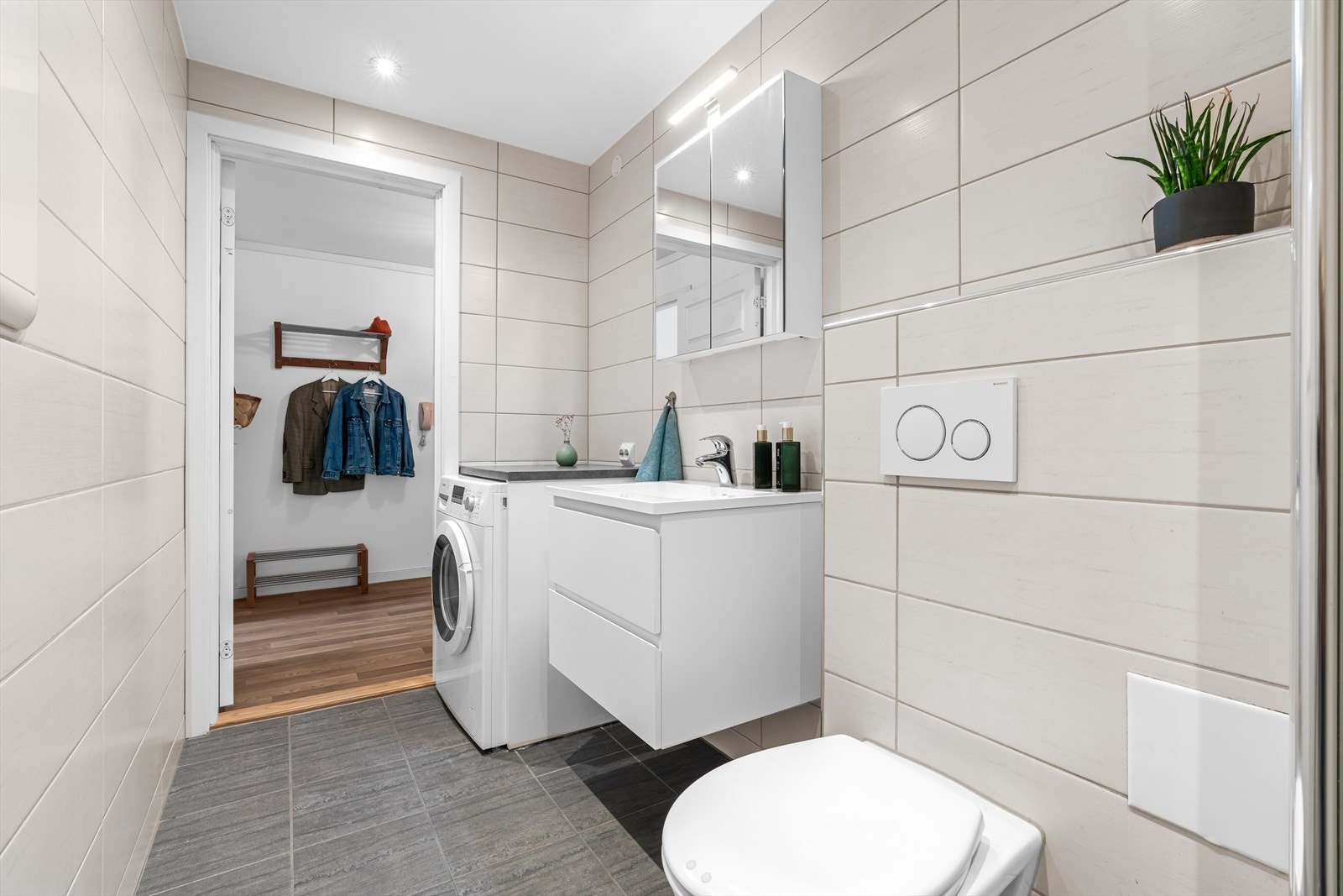 Det er opplegg for vaskemaskin med tilhørende benkeplate som gir gode arbeidsflater og ekstra oppbevaringsmuligheter. Downlights i himling bidrar til et behagelig lys, og helheten gir et funksjonelt og innbydende bad. Galleribilde