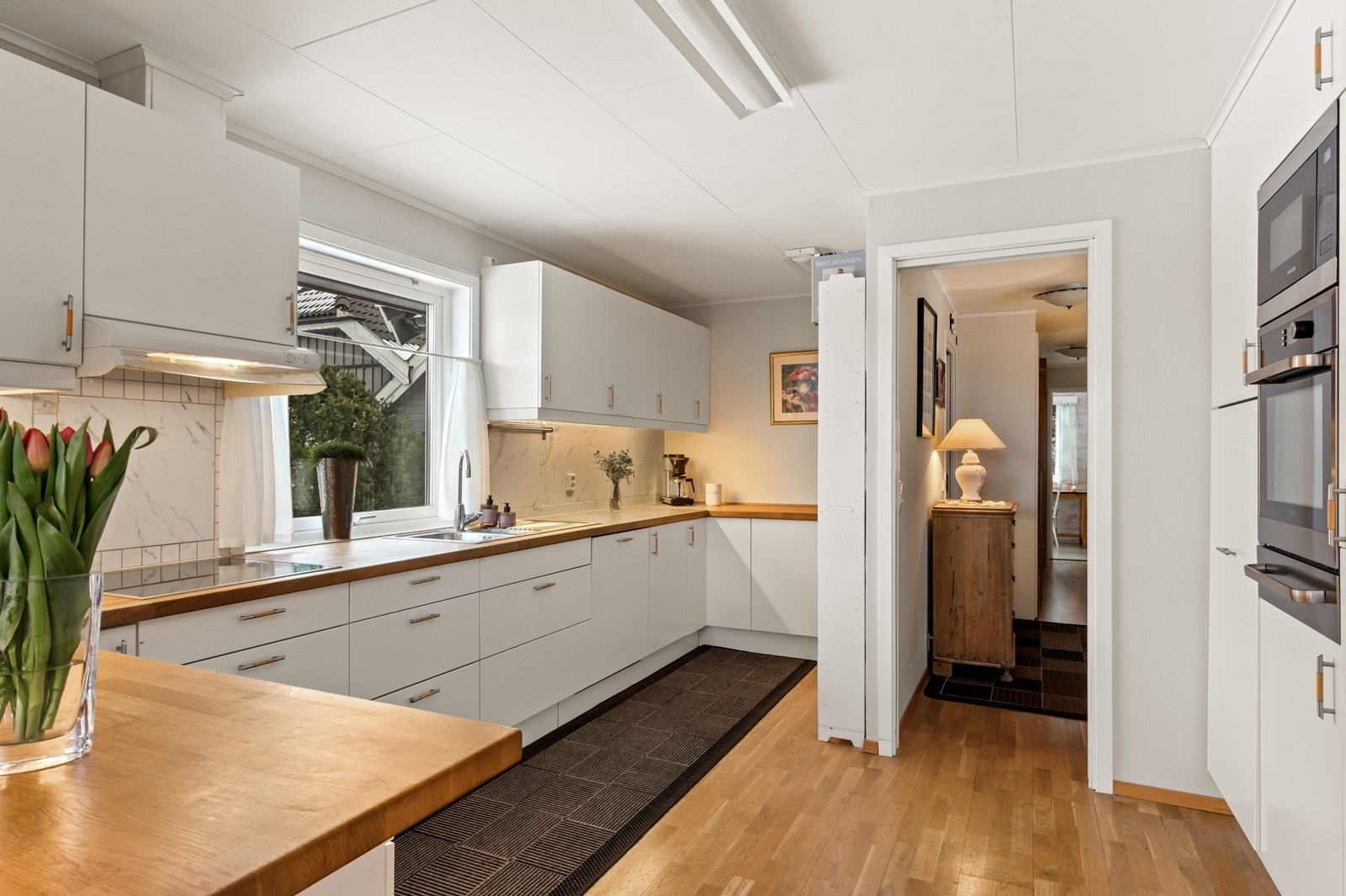 Kjøkkenet er romslig og har inngang både fra gangen og i fra stuen. På kjøkkenet er det en moderne innredning fra 2011 med fabrikklakkerte fronter og benkeplater i heltre. Galleribilde