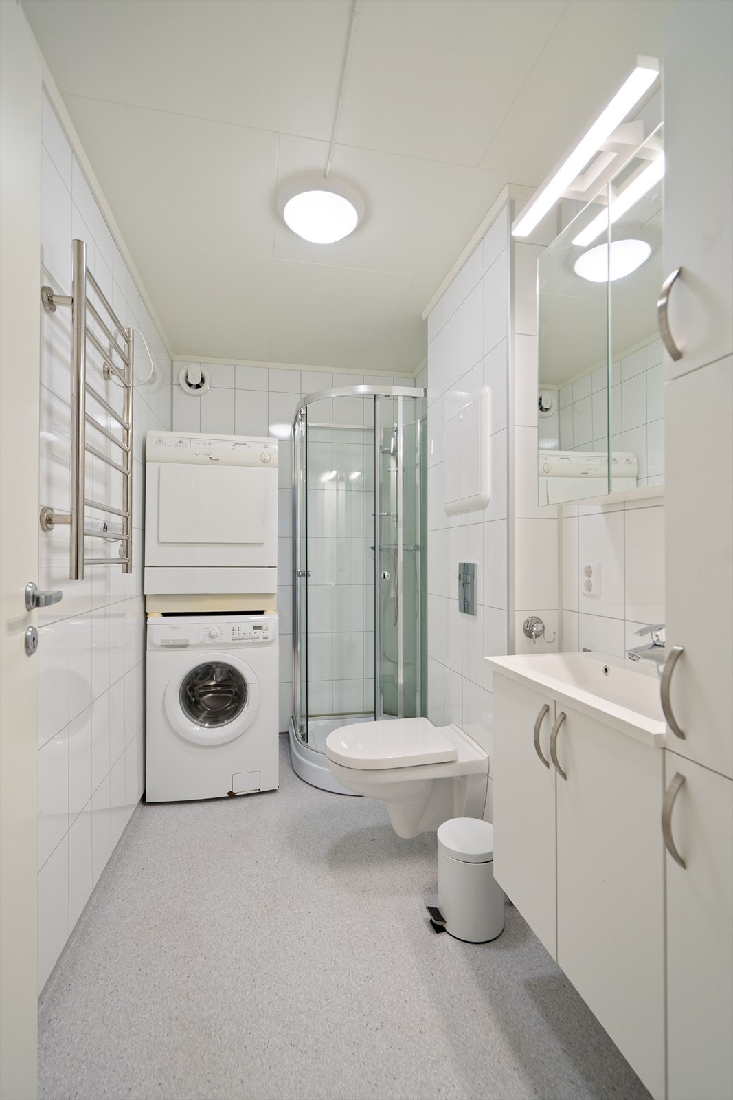Badet har baderomsplater på vegger og vinylbelegg med elektriske varmekabler i gulv. Innredning med nedfelt servant,veggmontert toalett,dusjkabinett og opplegg for vaskemaskin. Galleribilde