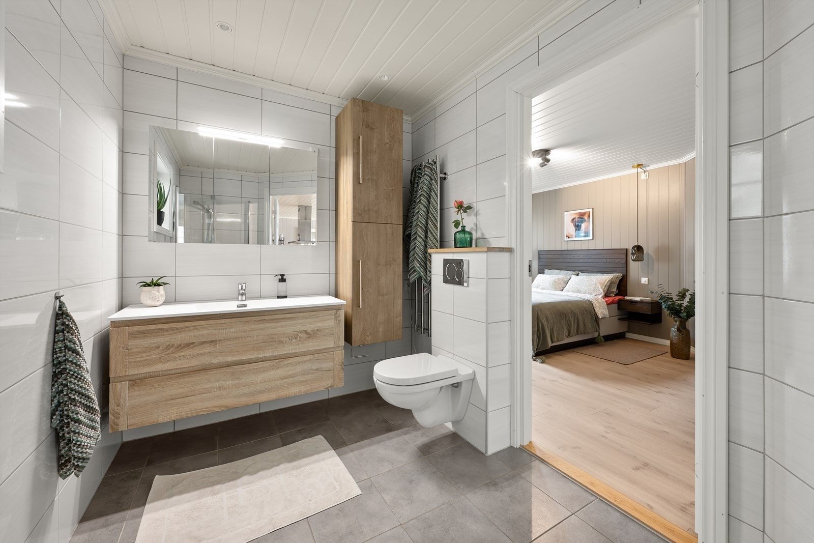 Badet er innredet med heldekkende servant med underskap og speil, innfeltbare dusjvegger i herdet glass og vegghengt toalett. Galleribilde