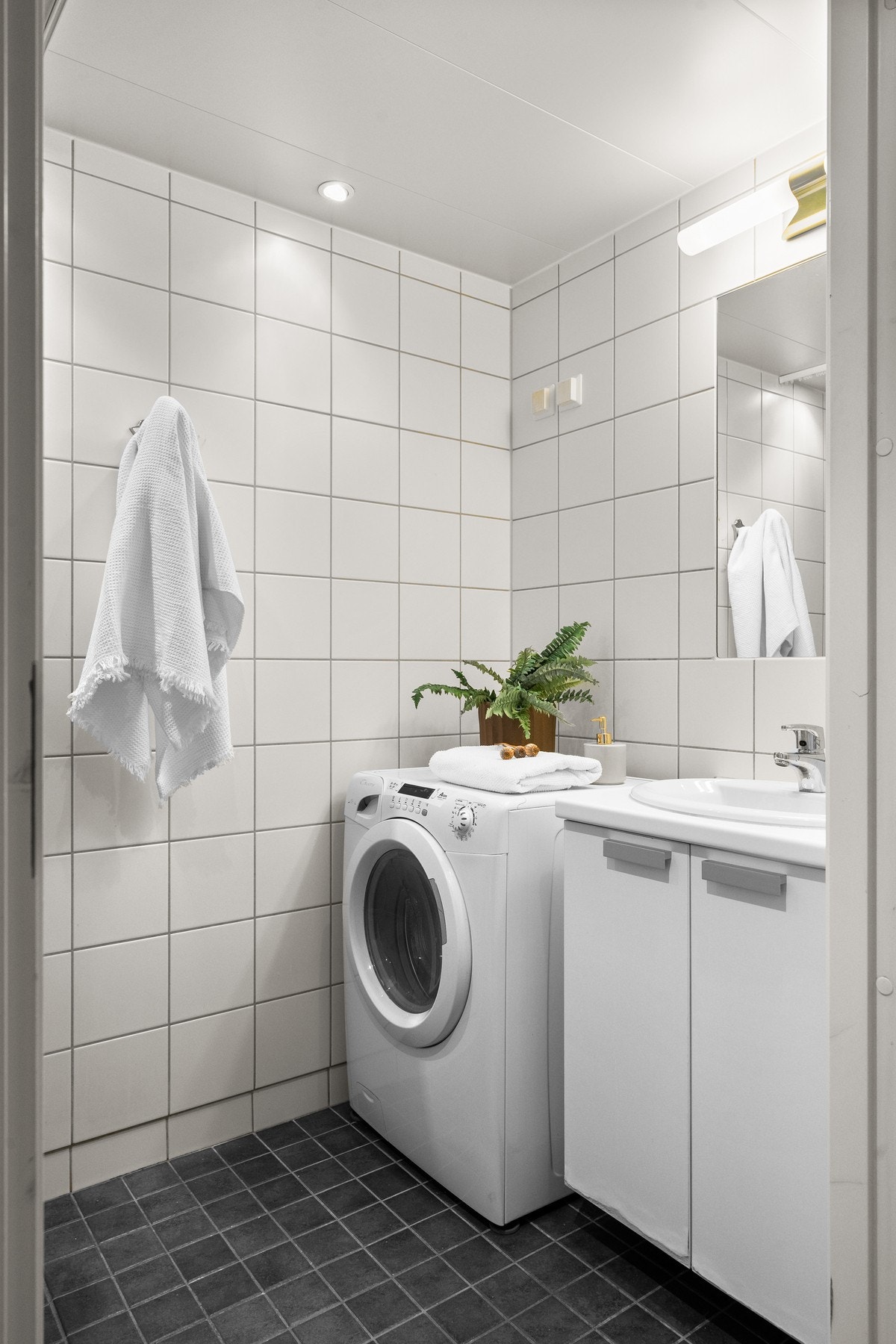 Lyst servantskap med nedfelt servant, speil og belysning over. I hjørnet er det plass og opplegg for vaskemaskin, samt tørketrommel over om ønskelig. Galleribilde