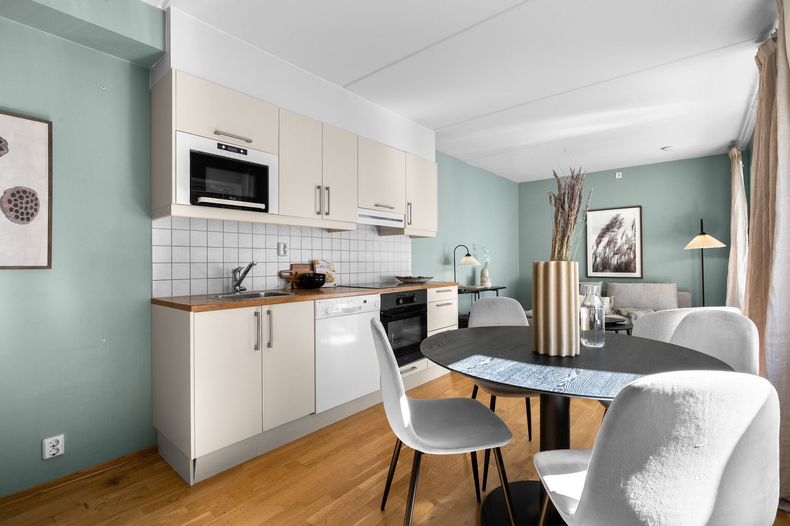 Innredningen har lyse glatte fronter og laminert benkeplate med nedfelt oppvaskkum. Praktisk med lyse fliser i benkeryggen og belysning under overskapene. Galleribilde