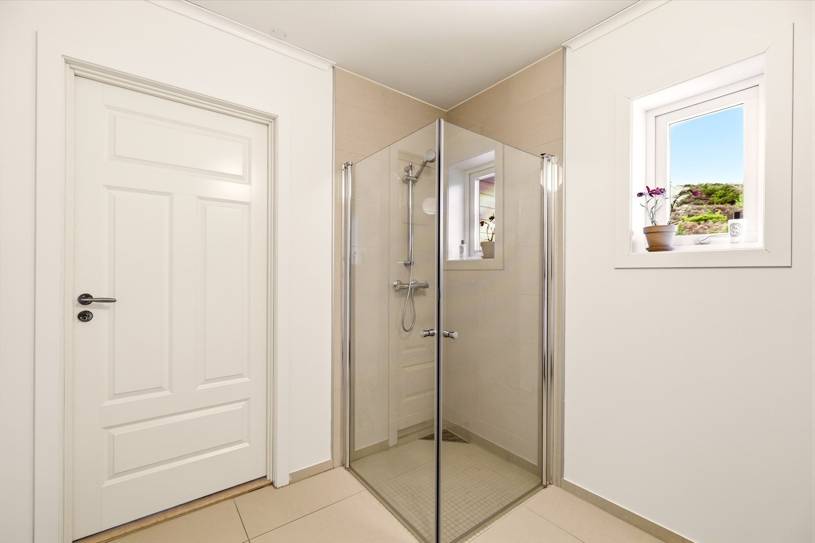 Dette badet inneholder baderomsmøbel med slette fronter, heldekkende servant, speil, vegghengt toalett og dusj med innfellbare dører. Galleribilde