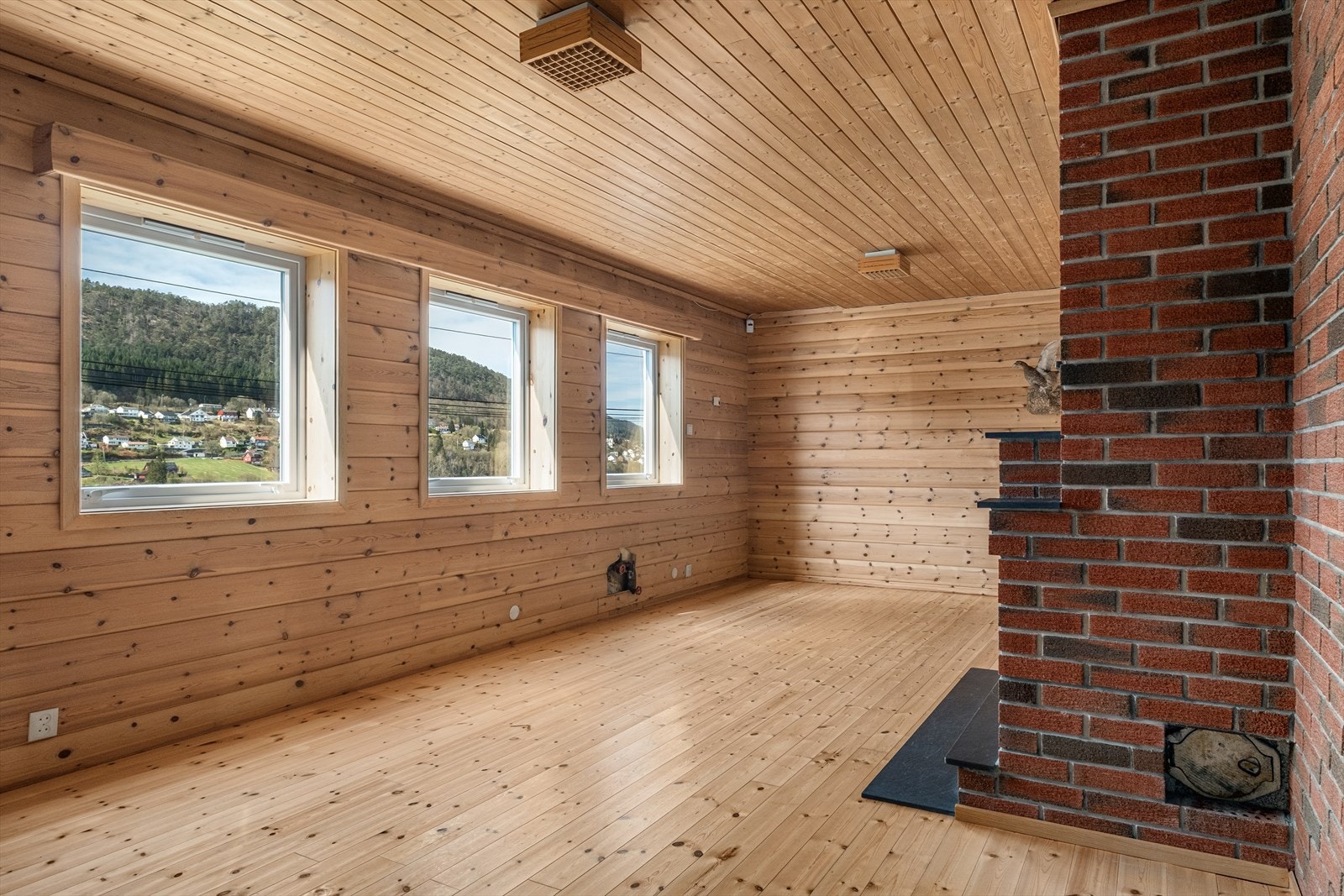 Romslig peisestue med panel på vegger og i tak. Galleribilde