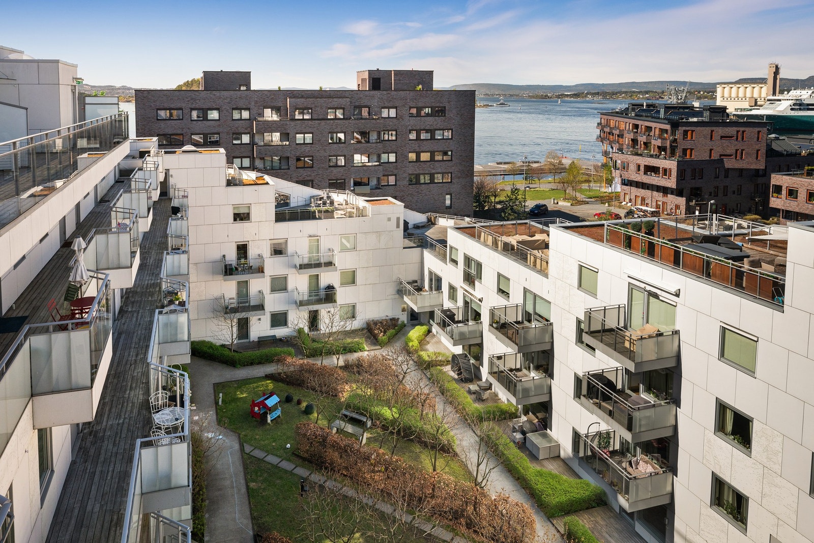Pent opparbeidet atrium med lekehus for barna, flere sitteplasser og grønne omgivelser hvor du kan nyte en kopp kaffe. Galleribilde