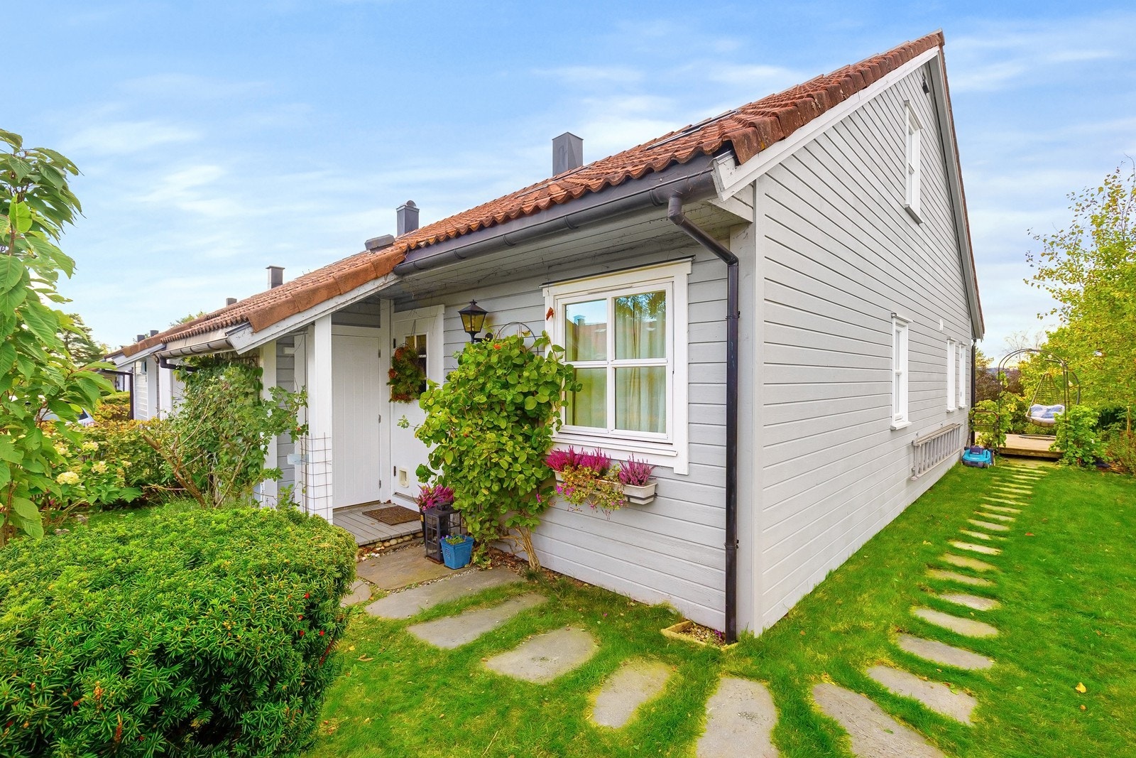 Innbydende og usjenert inngangsparti som er overbygd og har adkomst til utvendig bod for lagring. Sti med skifer til terrasseplattingen. Galleribilde
