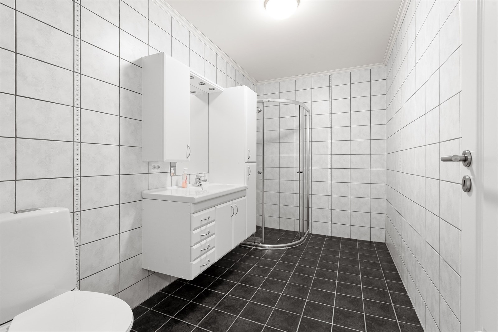 Bad i utleieleiligheten er flislagt og har en stor og romslig innredning, dusjhjørne og wc. Galleribilde