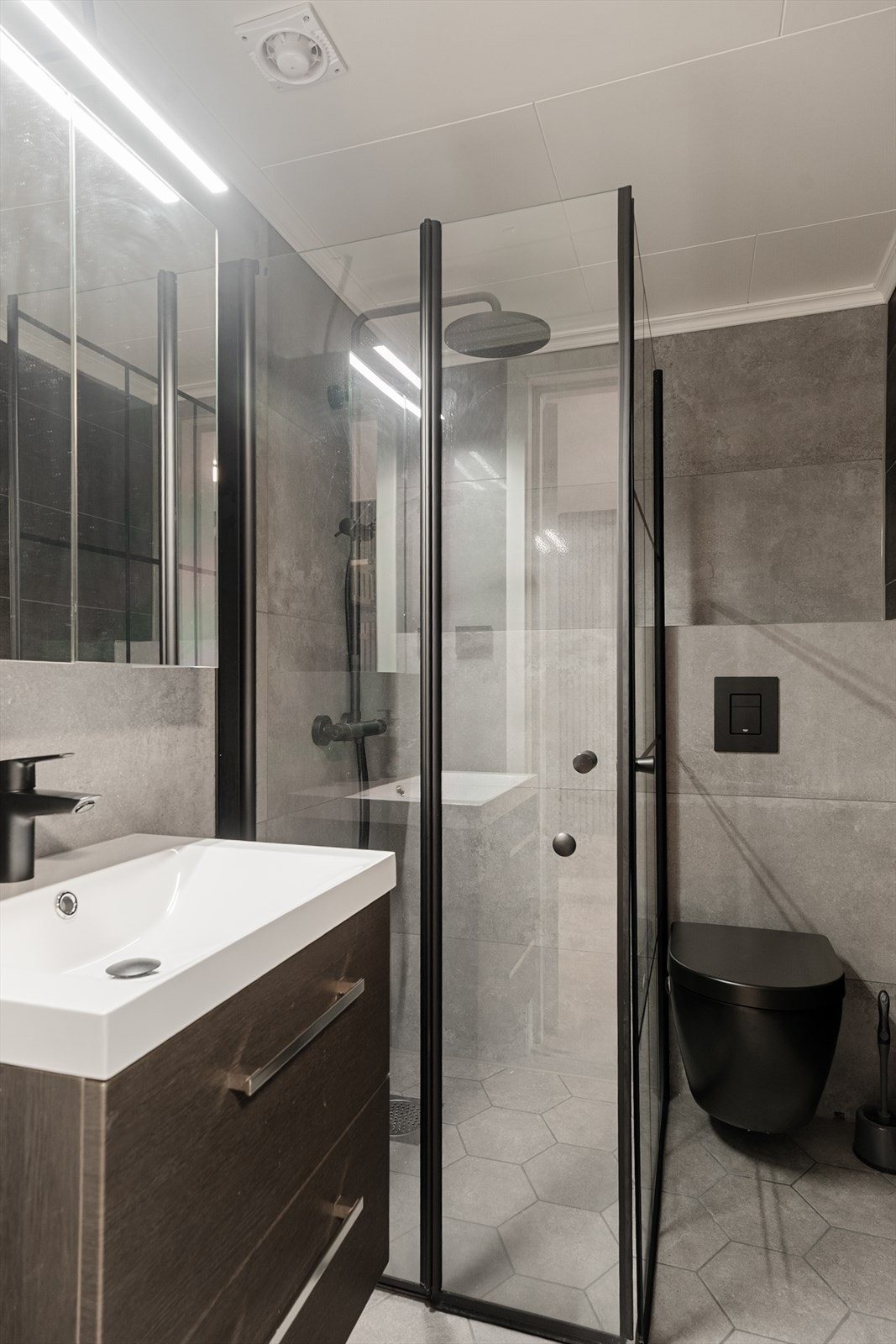 Bad i kjelleretasjen i samme delikate stil som hovedbadet i 1. etasje. Rommet har fliser på vegger og malte plater i himlinger. Flislagt gulv med varmekabler. Rommet er innredet med dusjnisje, veggmontert toalett og baderomsmøbel med servant. Galleribilde