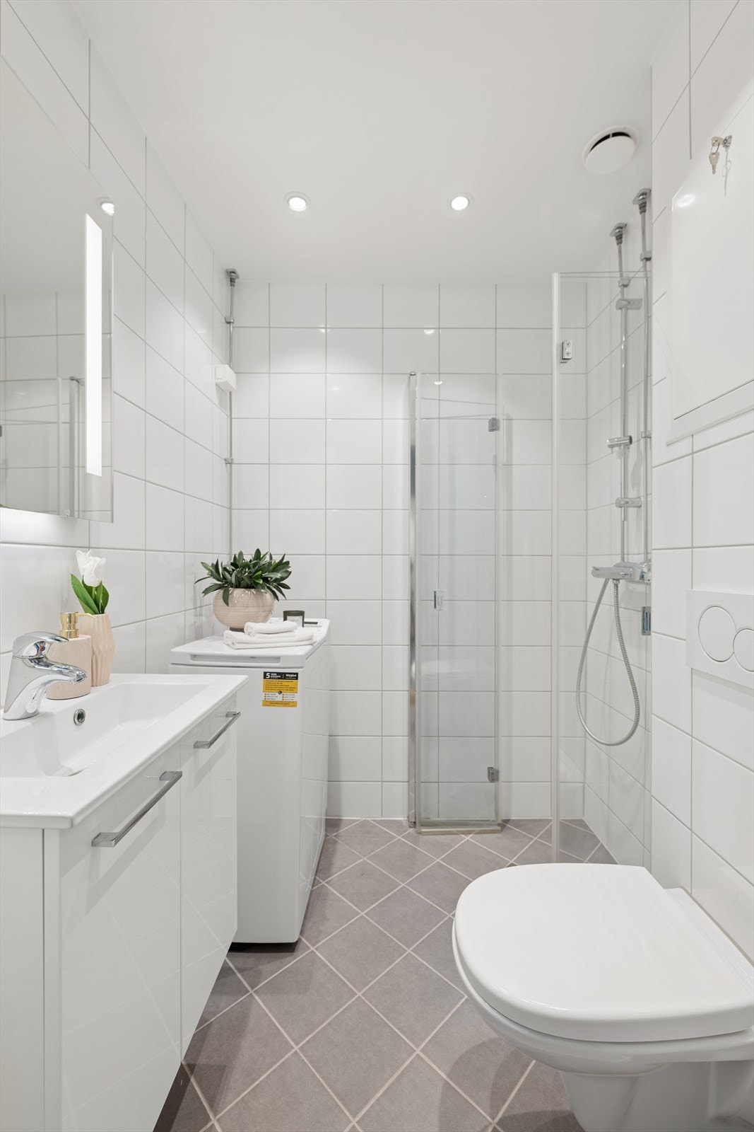 Flislagt baderom fra 2017 som er med varmekabler i gulv. Badet er utstyrt med servant, klosett, dusj på gulv og opplegg for vaskemaskin. Galleribilde
