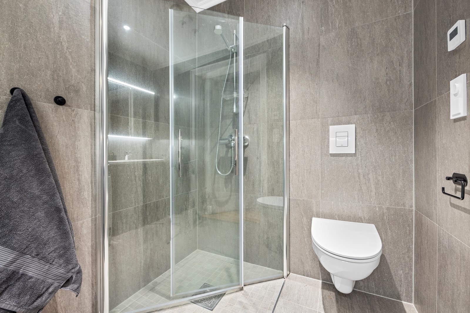 Badet er utstyrt med heldekkende servant med underskap, speilskap med lys, dusjnisje og toalett Galleribilde