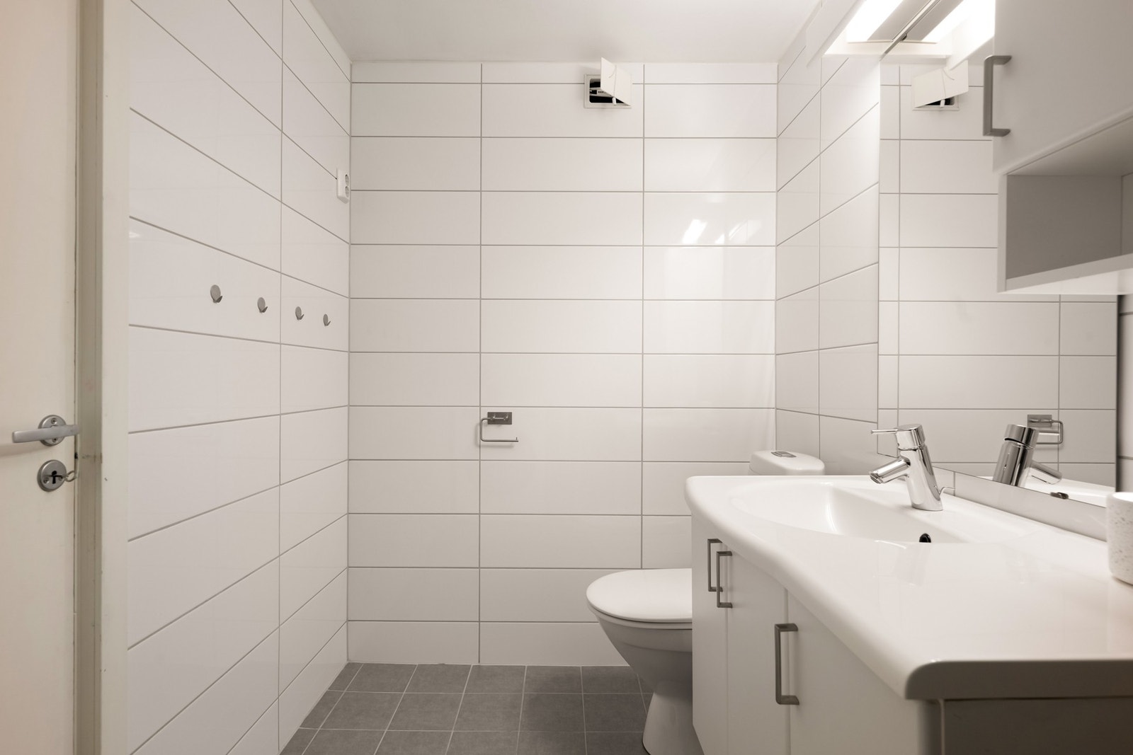 Badet er utstyrt med dusjhjørne, opplegg for vaskemaskin, baderomsinnredning og gulvstående wc Galleribilde