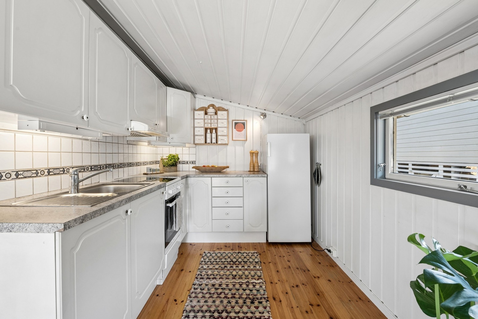 Lyst og parktisk kjøkken med profilerte fronter og benkeplate med laminert overflate. Galleribilde