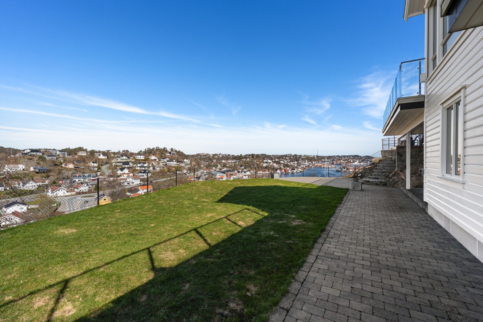 Romslig uteområde med plen og panorama over sjø og nærområde. Galleribilde