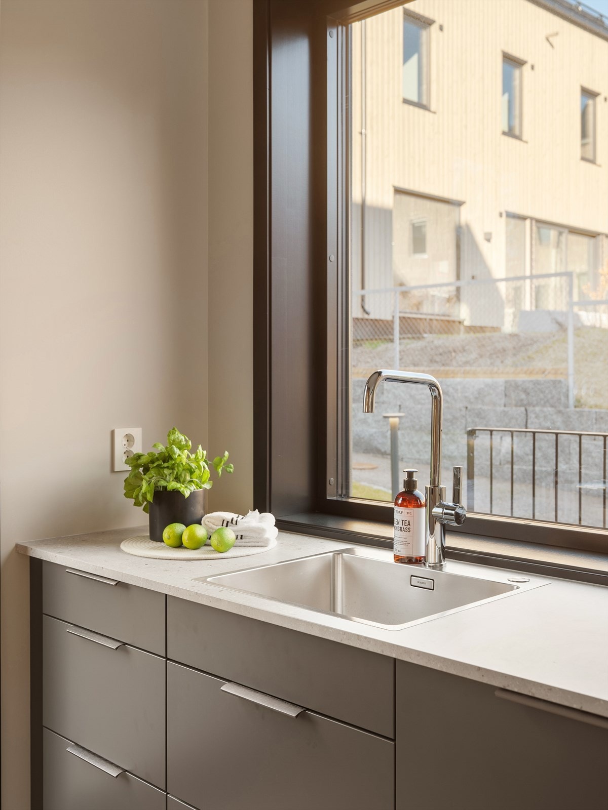Kjøkkenet har mørke, slette fronter og Terrazzo 20 mm laminat benkeplate med nedfelt oppvaskkum Galleribilde