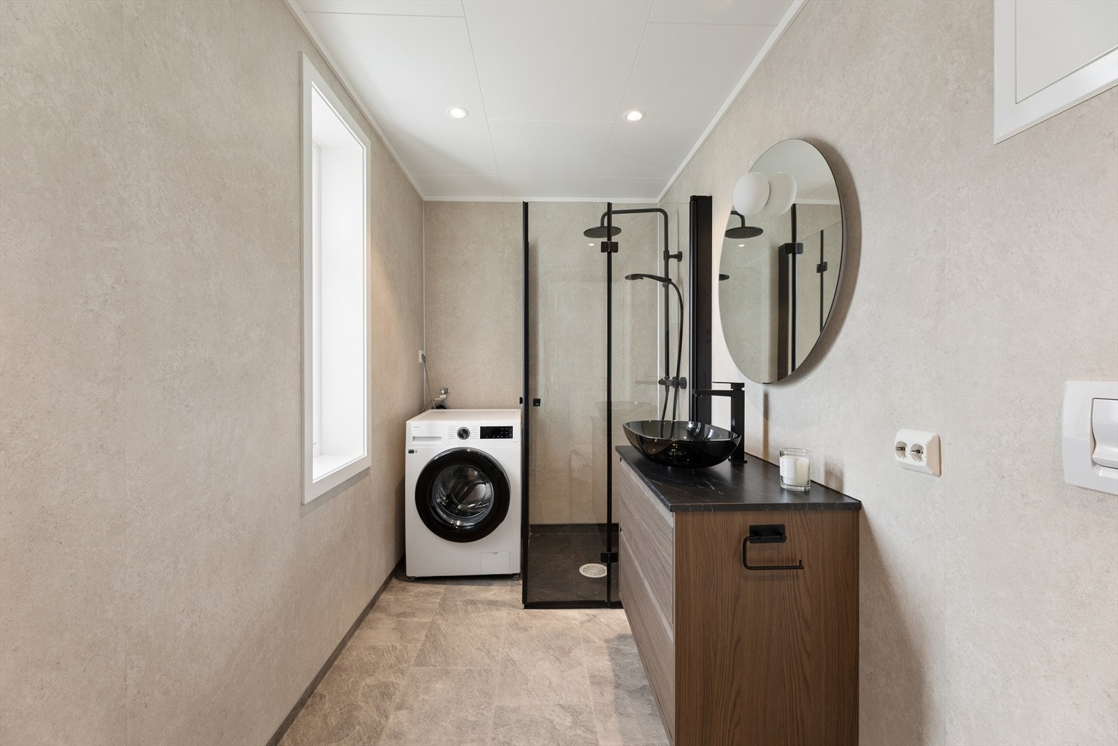 Badet er lyst og moderne, med stilrene baderomsplater på veggene, himlingsplater med spotter og vinylbelegg med varmekabler på gulvet. Galleribilde