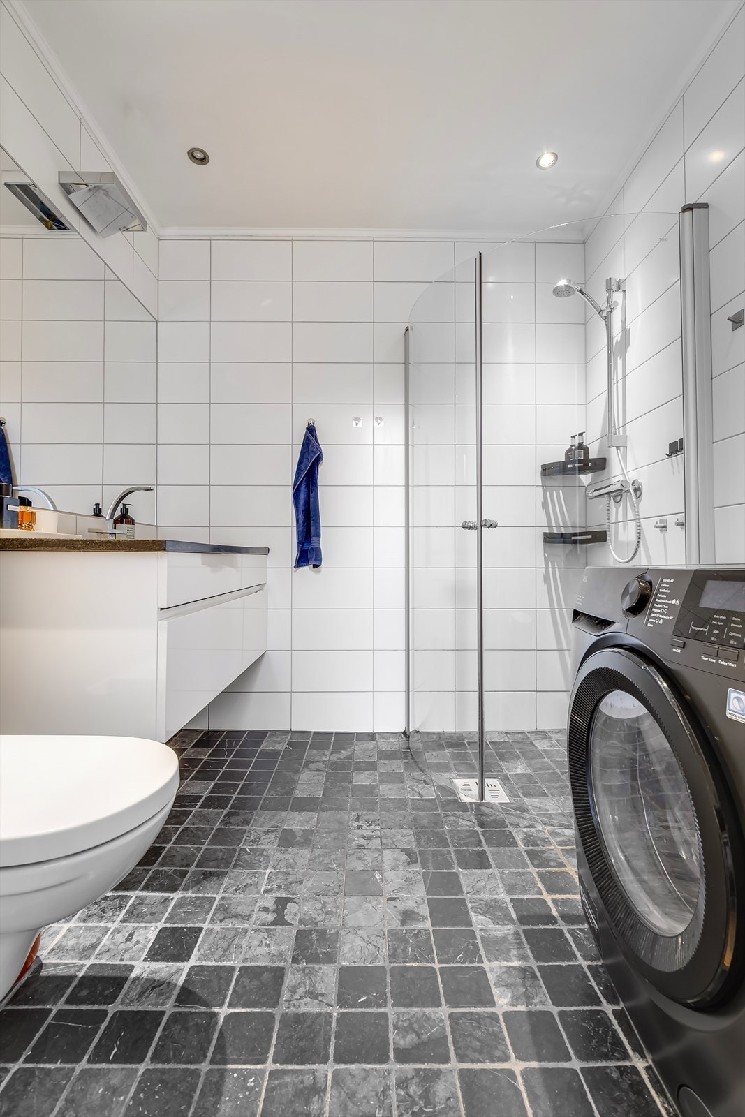 Badet har mørke 10x10 fliser på gulv og lyse 20x40 fliser på veggene. Galleribilde