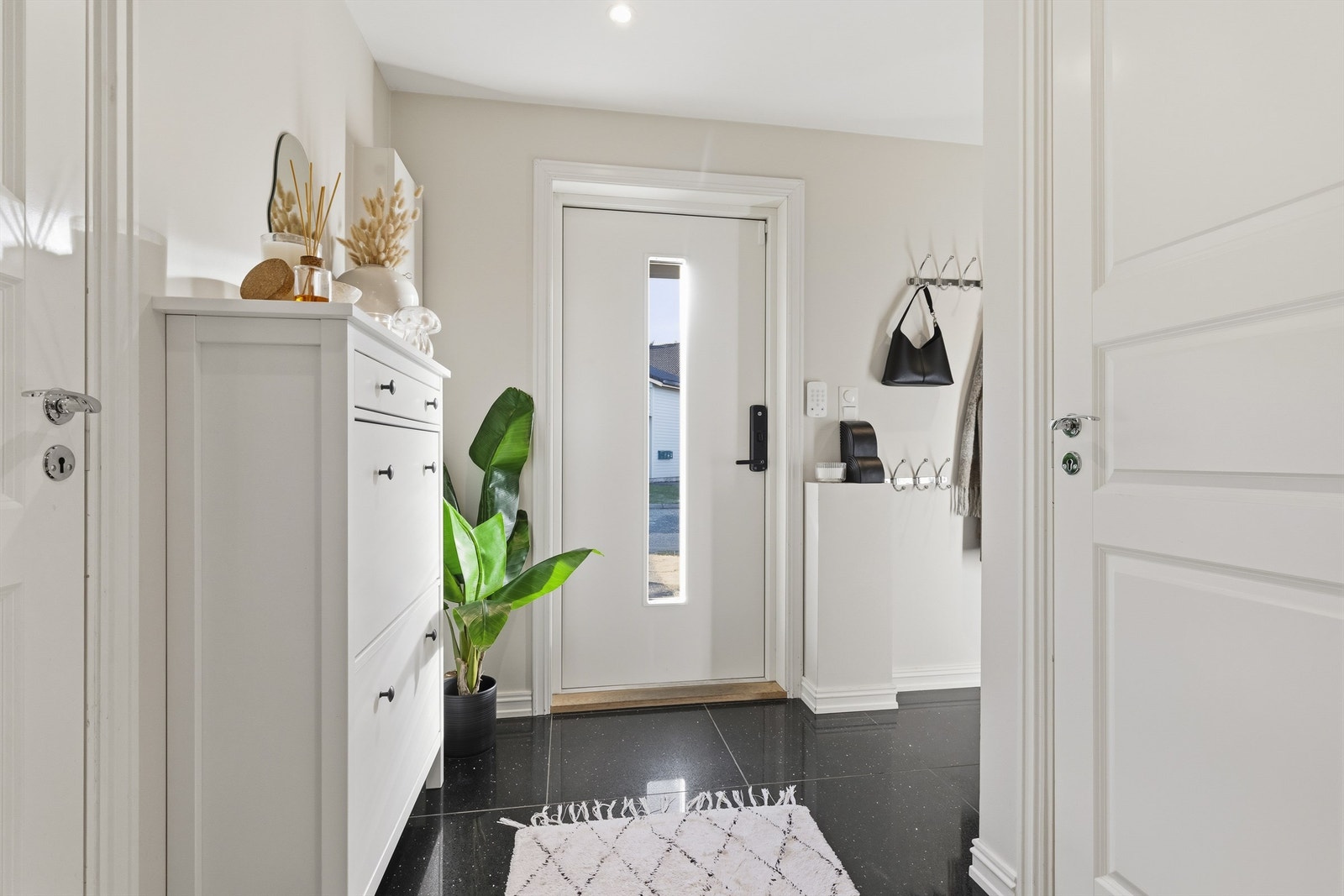Innbydende entré med plass til oppheng av tøy og oppbevaring av sko. Flislagt gulv. Downlights i himling Galleribilde