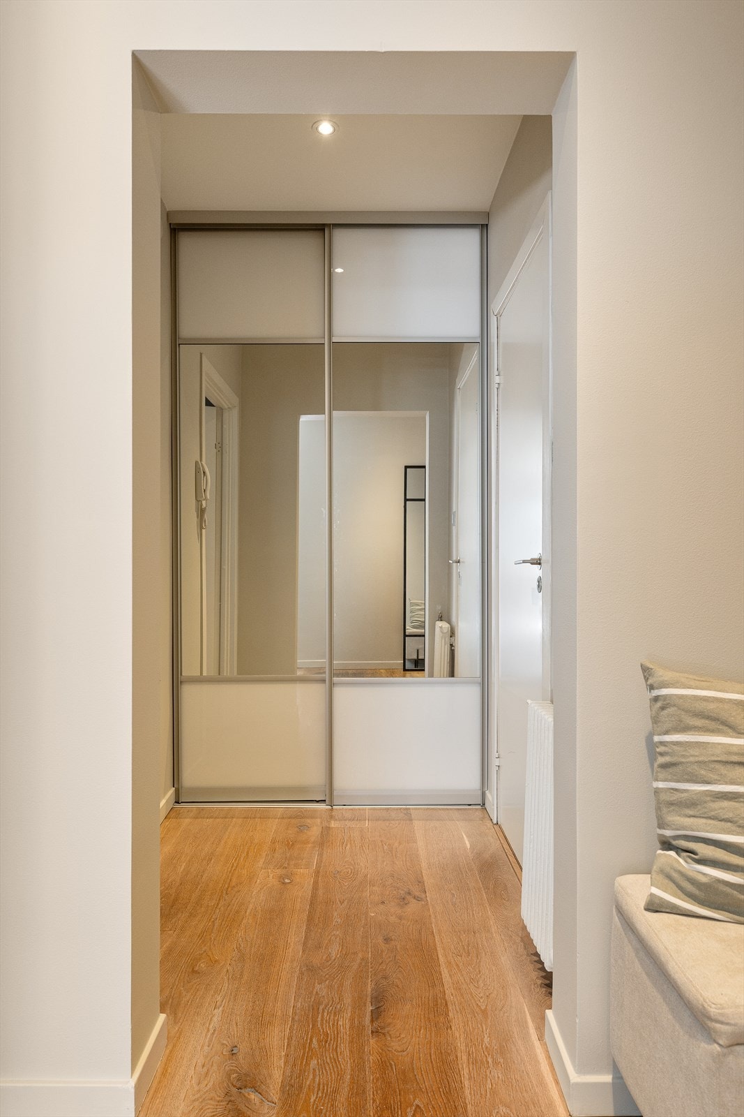 I tilknytning til entréen ligger en gang med praktisk skyvedørsgarderobe, perfekt for oppbevaring av yttertøy og sko. Galleribilde