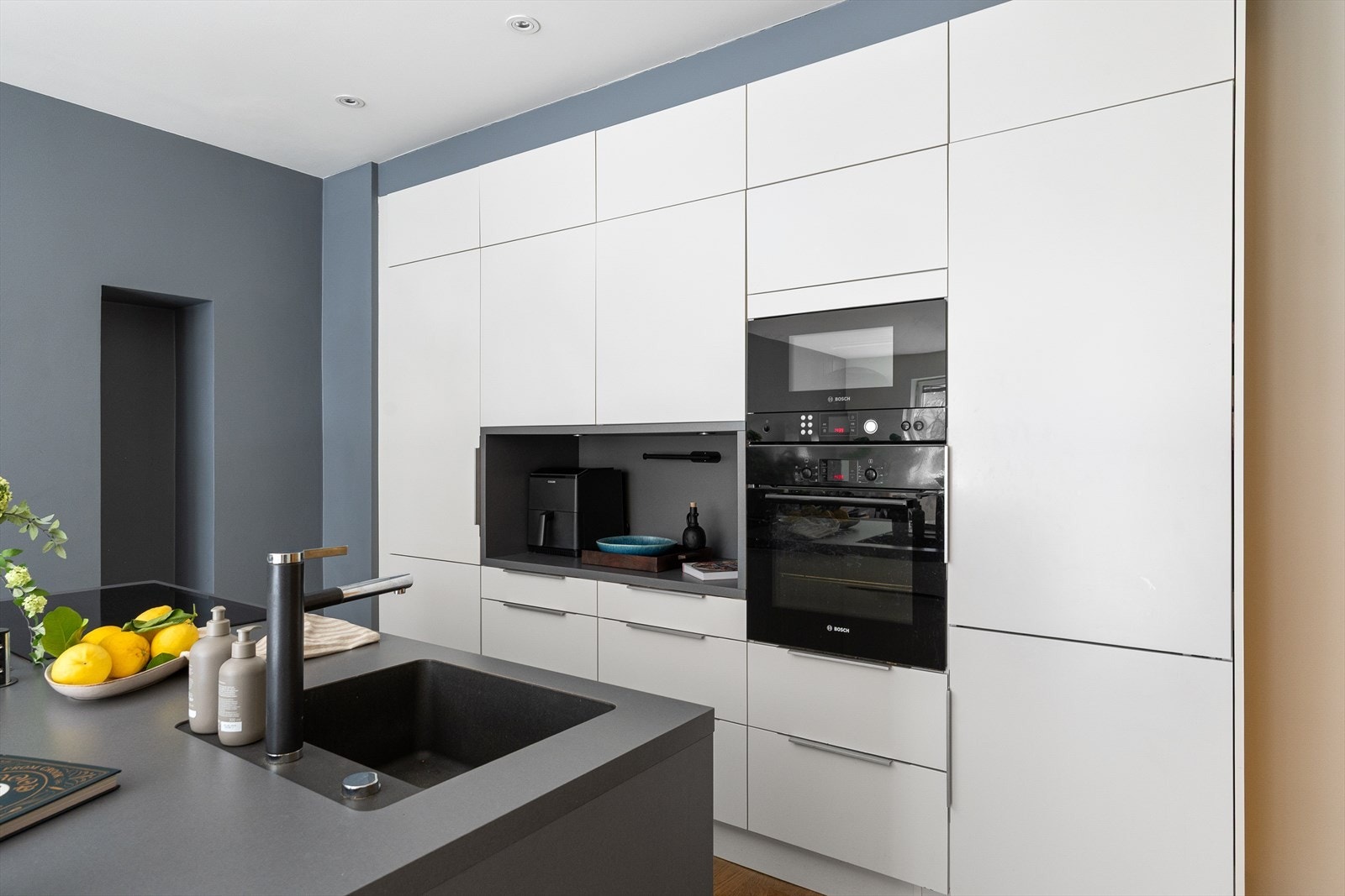 Stilrent kjøkken med innredning fra HTH med glatte fronter og laminert benkeplate med nedsenket oppvaskkum og ettgreps blandebatteri fra Blanco. Galleribilde
