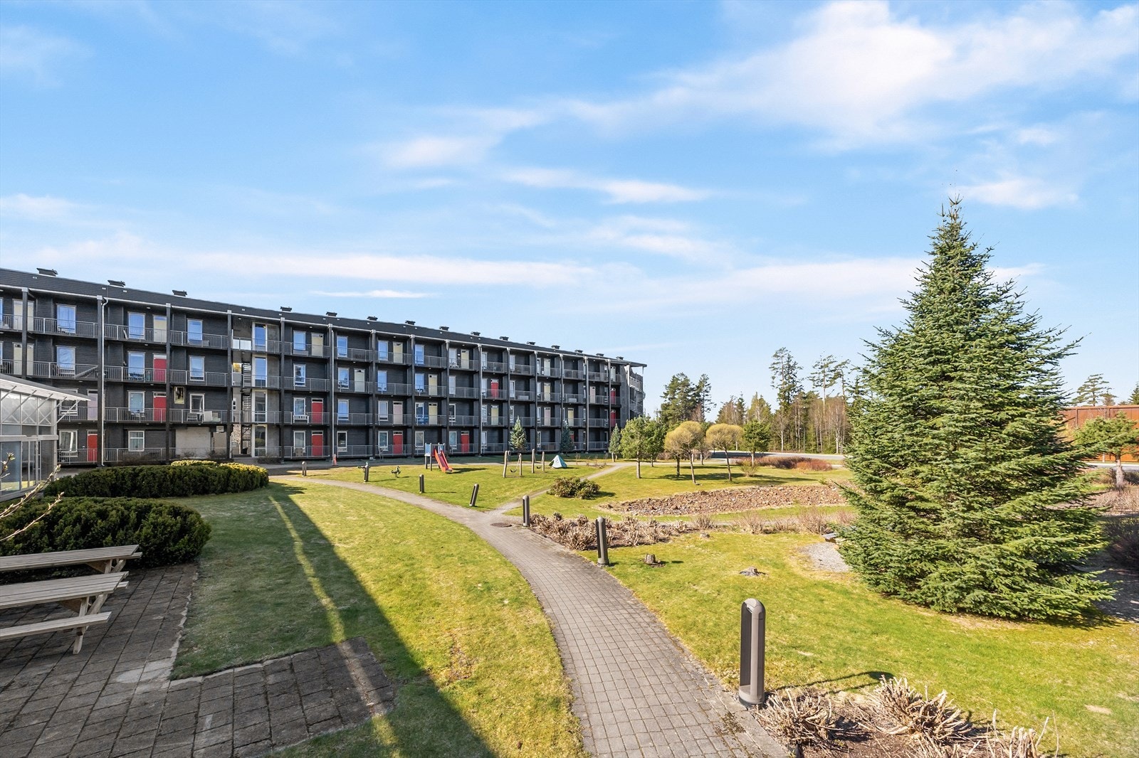 Velholdt felles tomt for borettslaget med plen, beplanting, internveier, belysning, sittegrupper og lekeareal. Galleribilde
