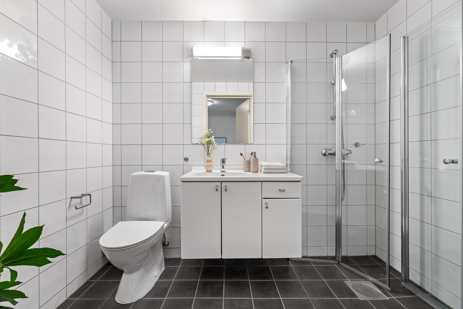 Badet er innredet med gulvstående toalett fra 2025, servant med underskap og et dusjhjørne fra 2020 Galleribilde