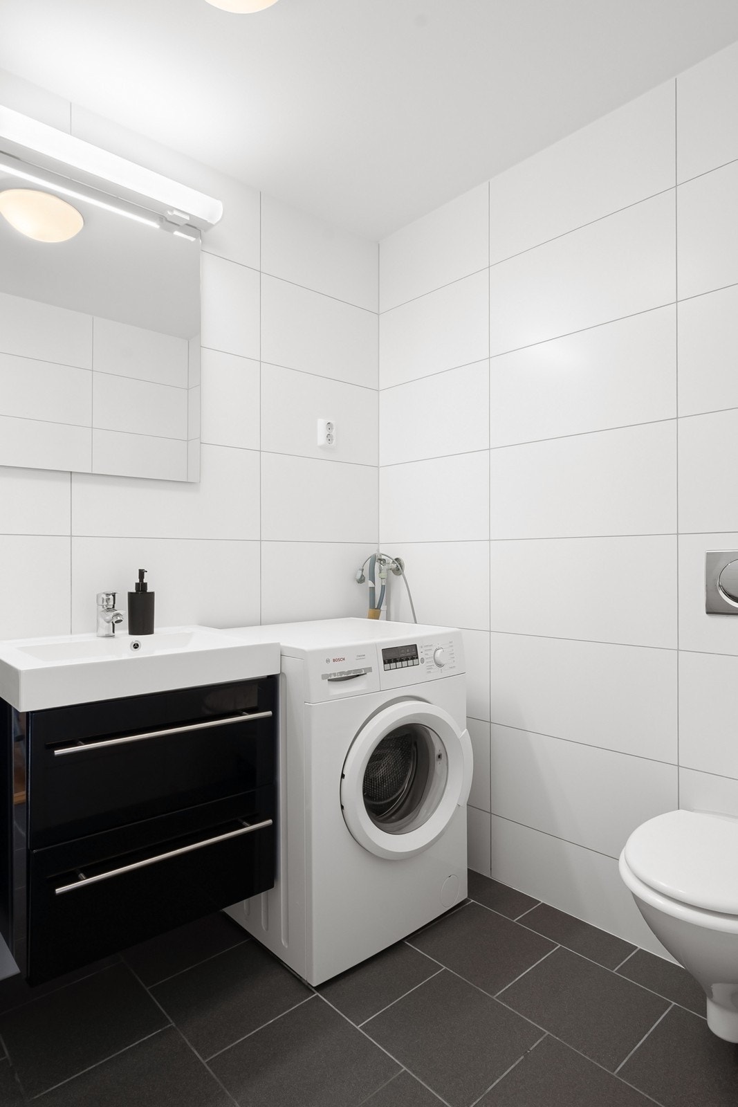 Videre har badet toalett, skuffeseksjon med heldekkende servant og røropplegg for vaskemaskin. Galleribilde