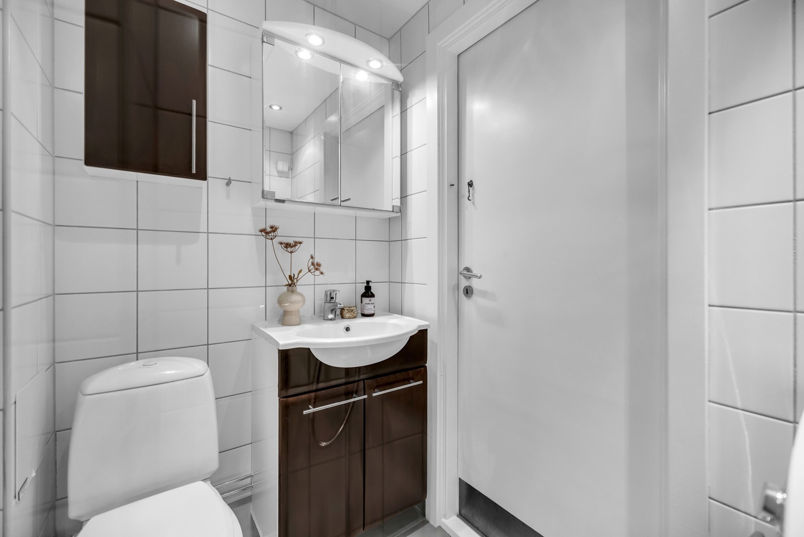 Badet er utstyrt med toalett, dusj med dusjvegger, servant med ettgreps blandebatteri i innredning, samt opplegg for vaskemaskin Galleribilde