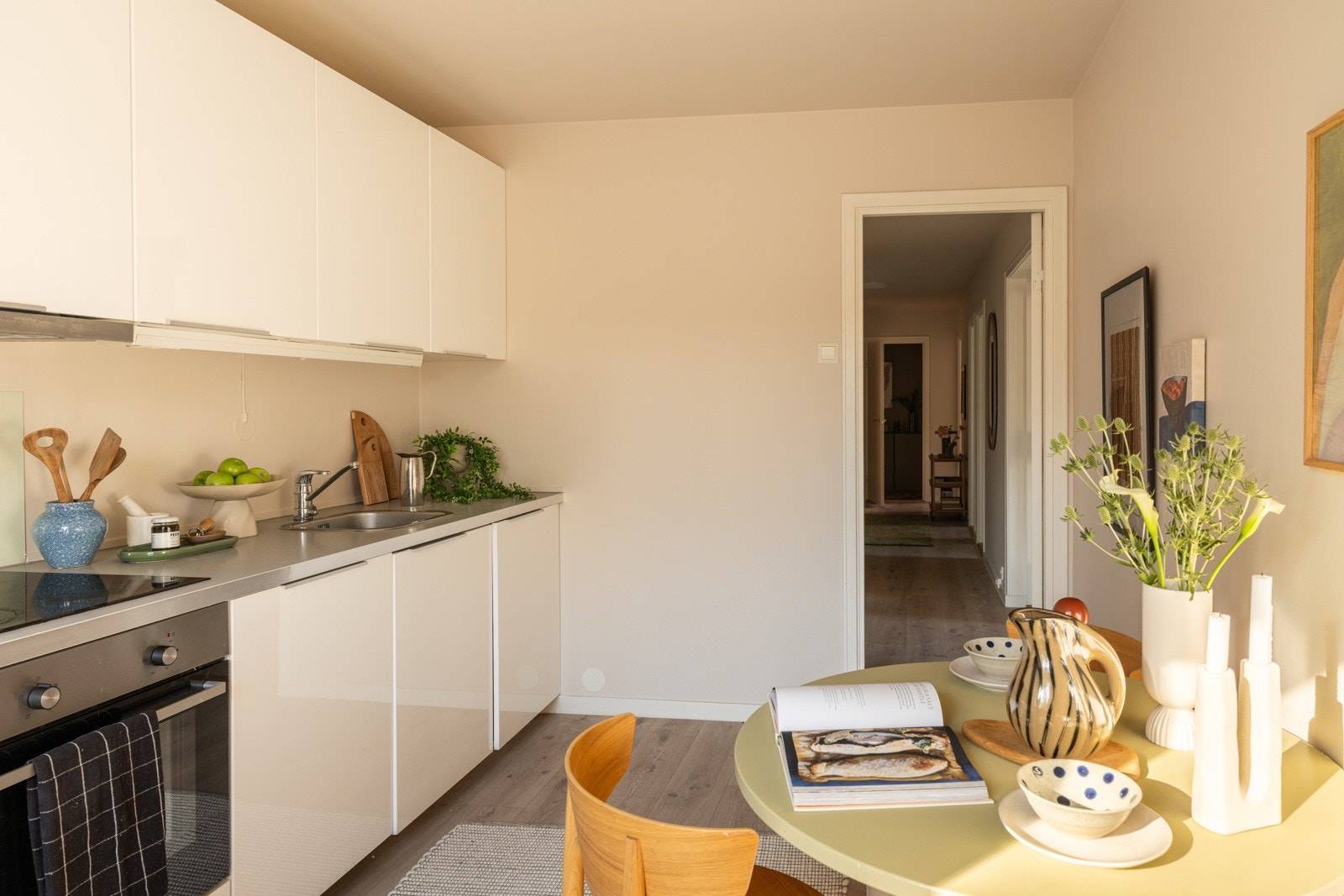Innredningen har hvite glatte fronter og laminert benkeplate med nedfelt oppvaskkum. Praktisk med belysning under overskapene. Galleribilde