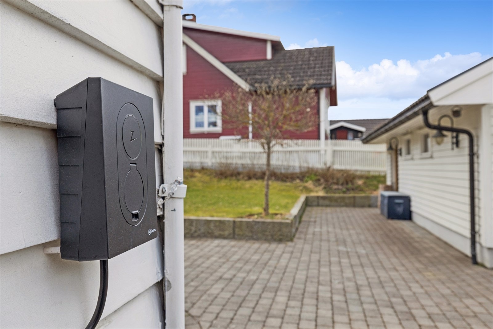 Det er installert elbillader på husveggen. Galleribilde