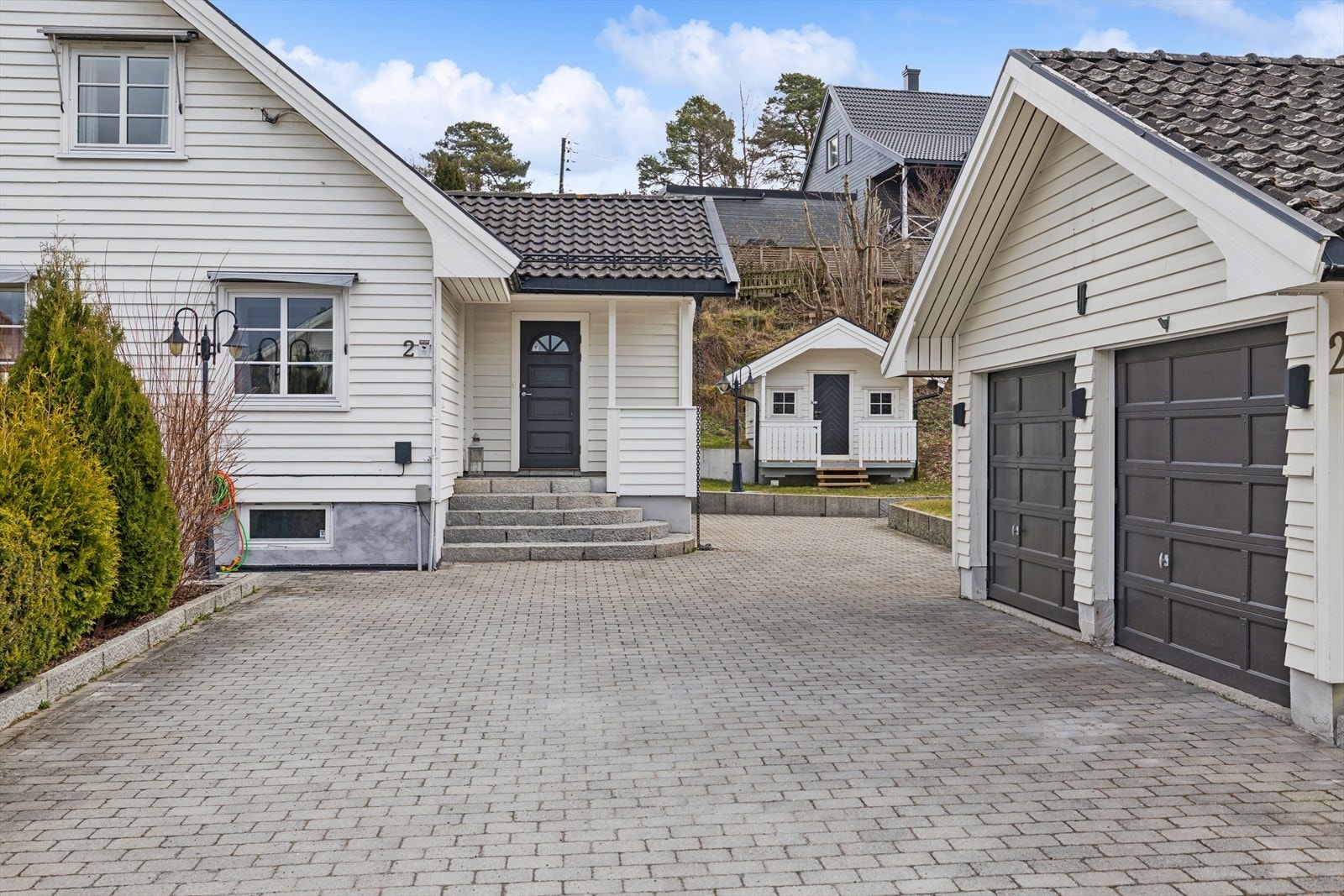 Belegningsstein på gårdsplassen gir et ryddig og vedlikeholdsvennlig inngangsparti. Galleribilde