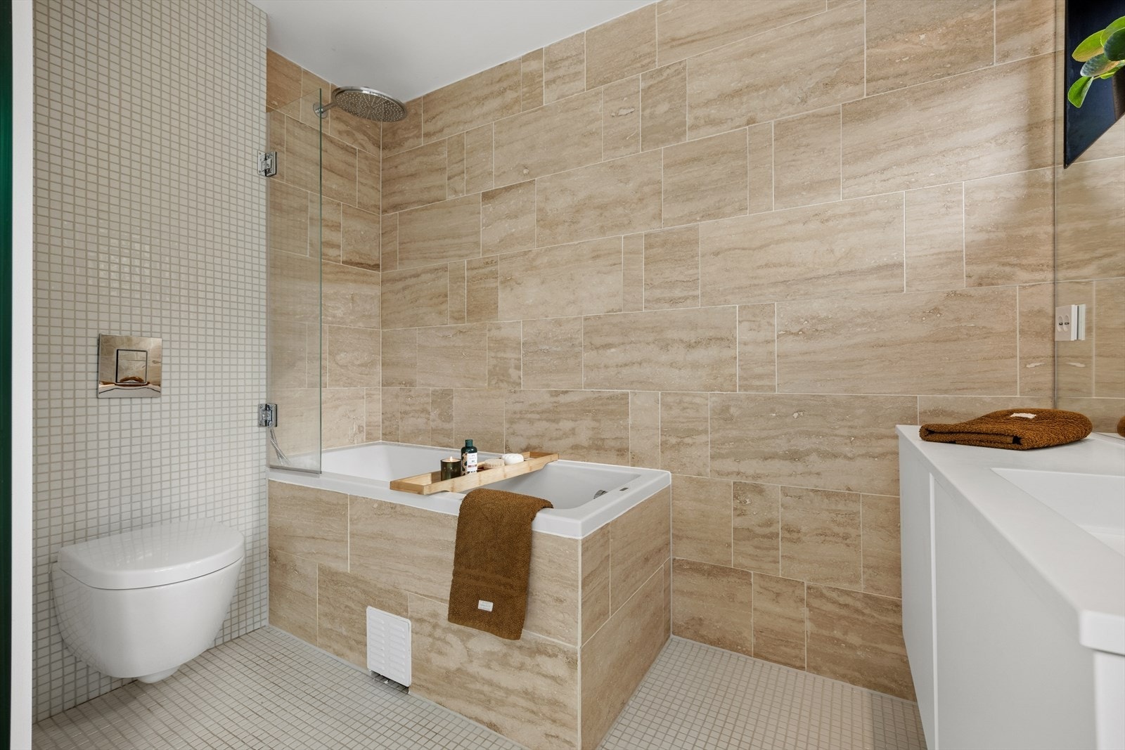 Badet er utstyrt med både badekar og dusj, med vegghengt toalett og servantinnredning. Galleribilde