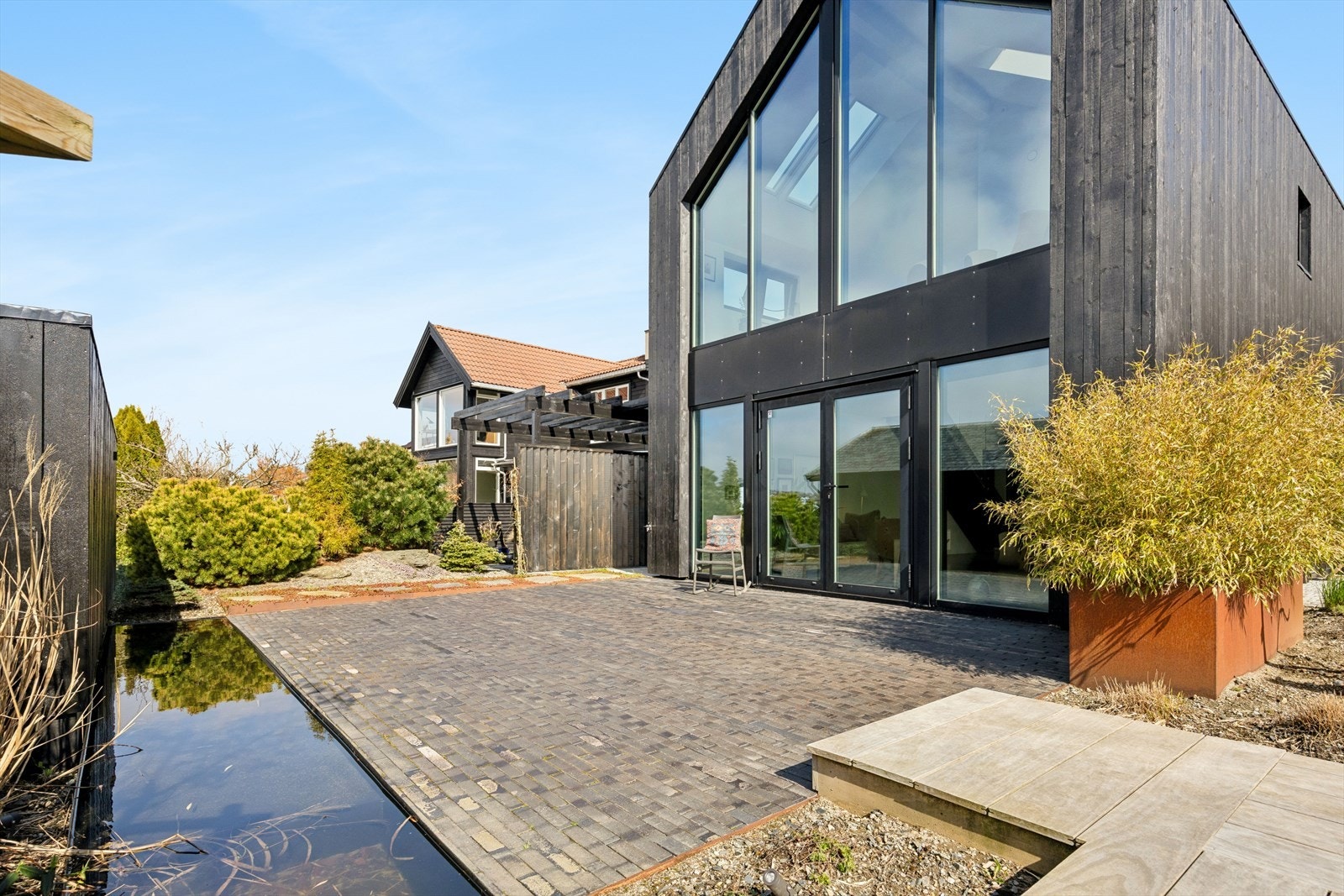 Vannspeilet er et elegant element i hagen som reflekterer himmelen og den moderne fasaden. Galleribilde