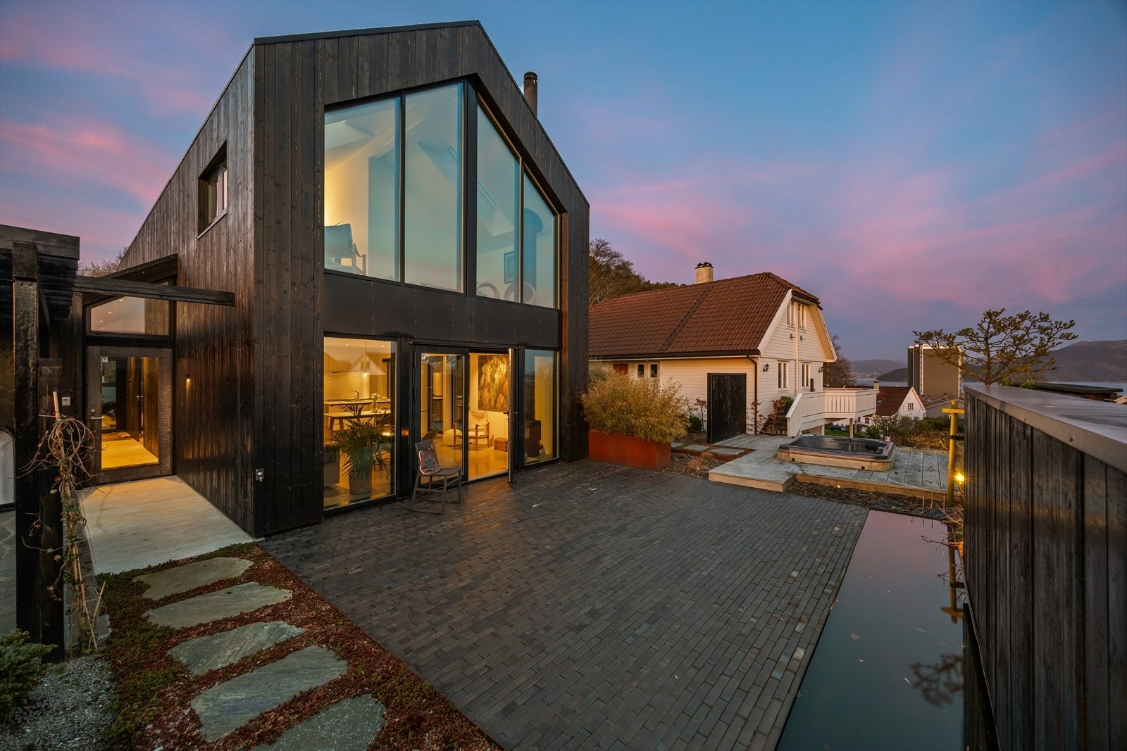 Her venter en arkitektonisk særpreget enebolig med et flott opparbeidet uteområde, komplett med vannspeil og jacuzzi. Galleribilde