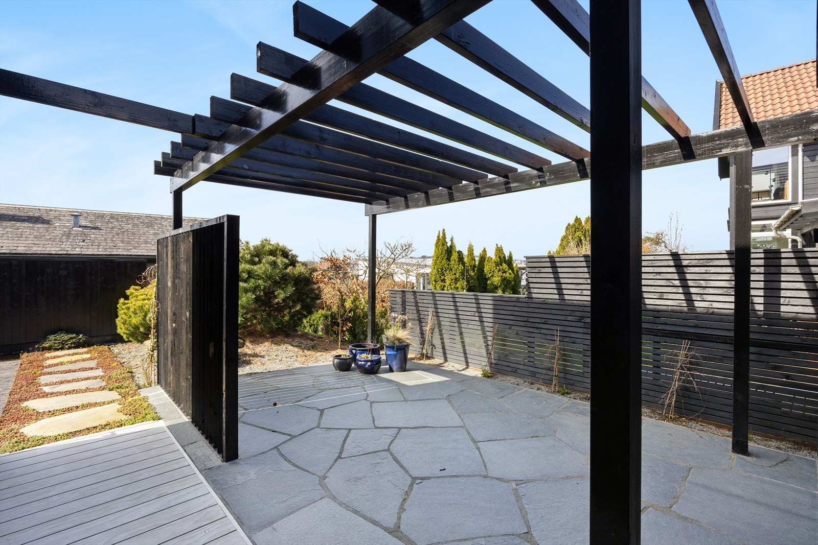 En overbygd pergola skaper en lun og definert sone i hagen, perfekt for en sittegruppe. Galleribilde