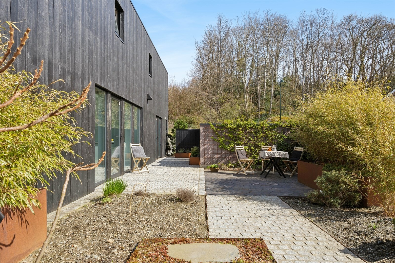 Baksiden av huset har også en skjermet uteplass med brostein og beplantning. Galleribilde
