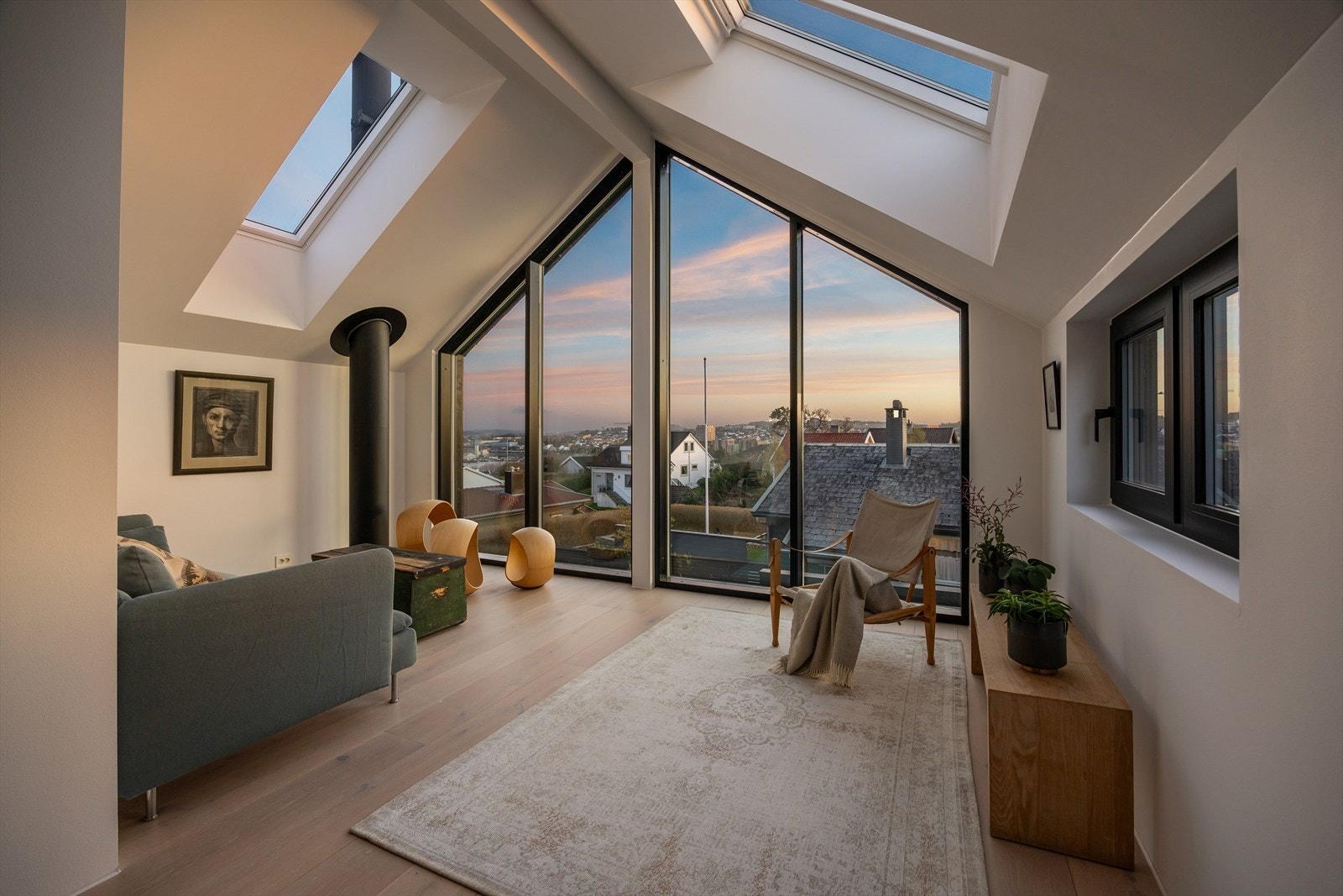 Loftstuen i andre etasje har en imponerende takhøyde og en hel gavlvegg i glass som rammer inn utsikten. Galleribilde