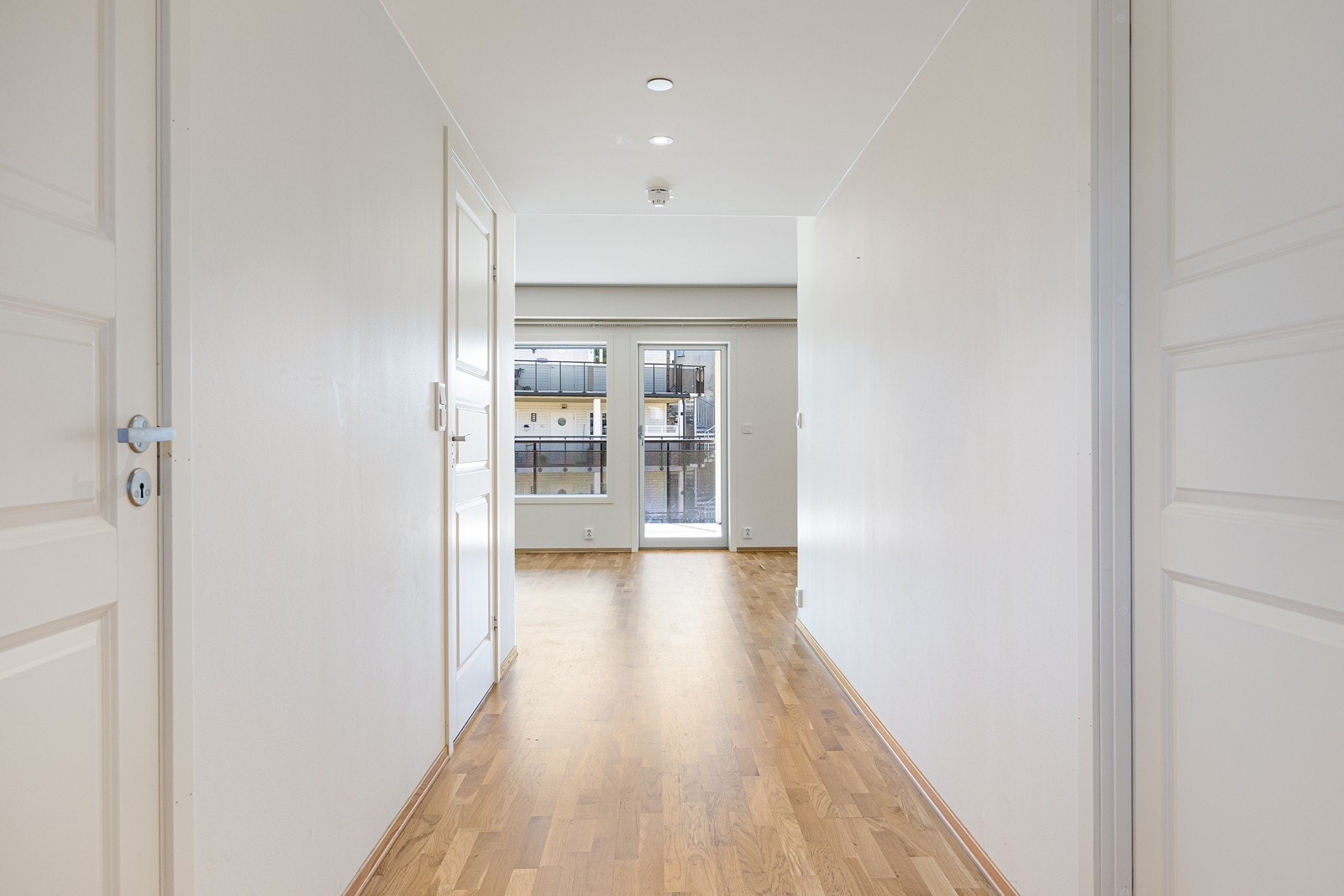 Veggene er lysmalte, i taket er det downlights og på gulvet er det parkett som glir sømløst over i den åpne kjøkken- og stueløsningen. Galleribilde