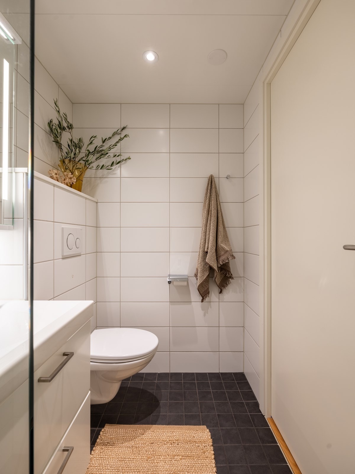 Baderommet er stilrent innredet med servant og skap, speil, høyskap, vegghengt toalett og dusjhjørne med glassdører. Galleribilde