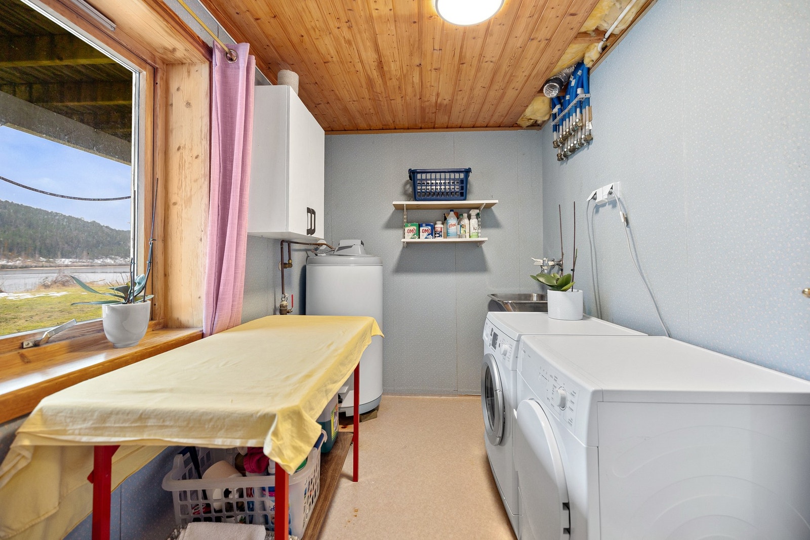 Vaskerommet er innredet med opplegg for vaskemaskin, utslagsvask og varmtvannsbereder, samt synlig røropplegg og fordelerskap. Overflatene består av belegg på gulv og plate-/tapetserte vegger, med himling i trepanel. Galleribilde