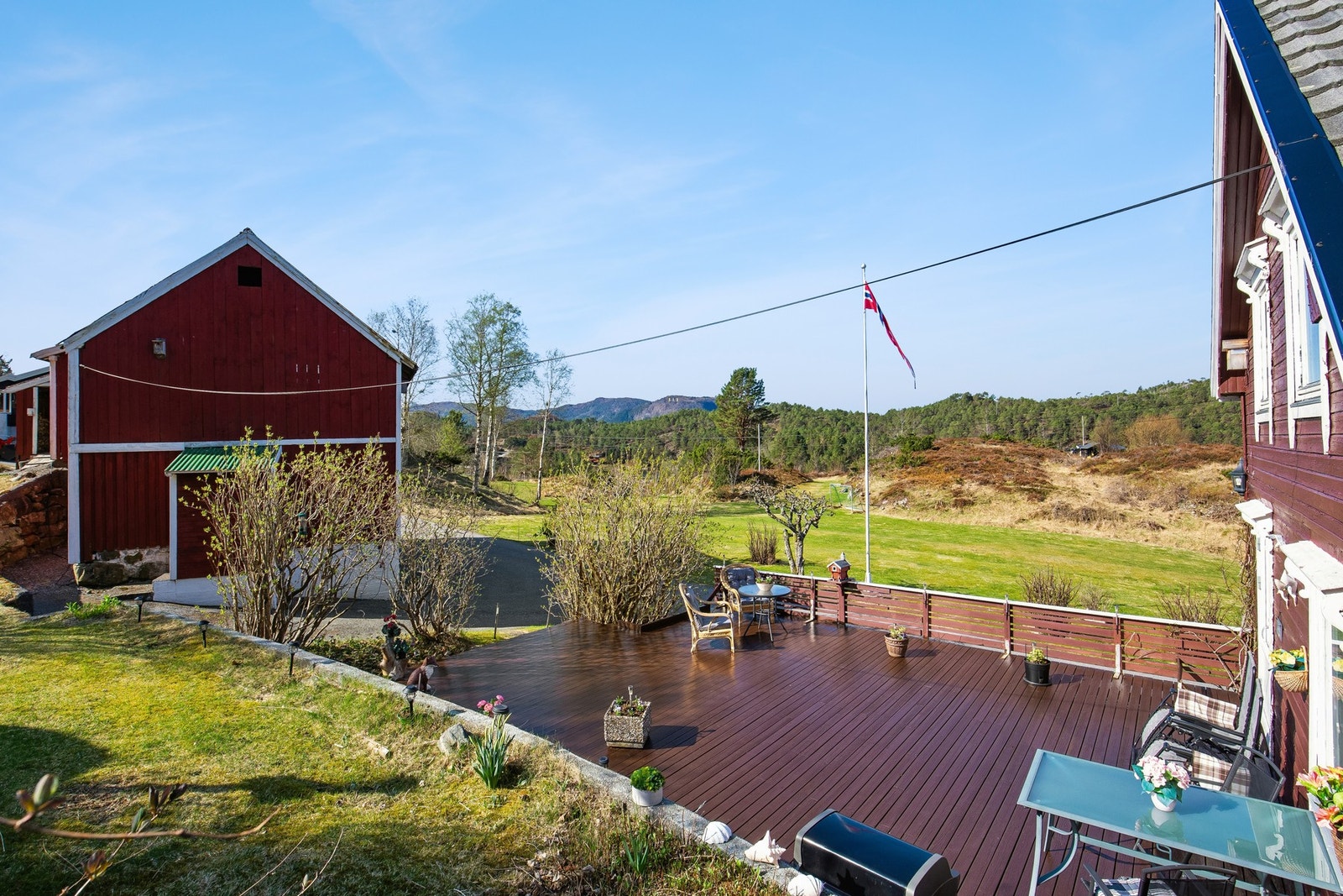 Pent opparbeidet uteområde med terrasse, plen og beplantninger Galleribilde