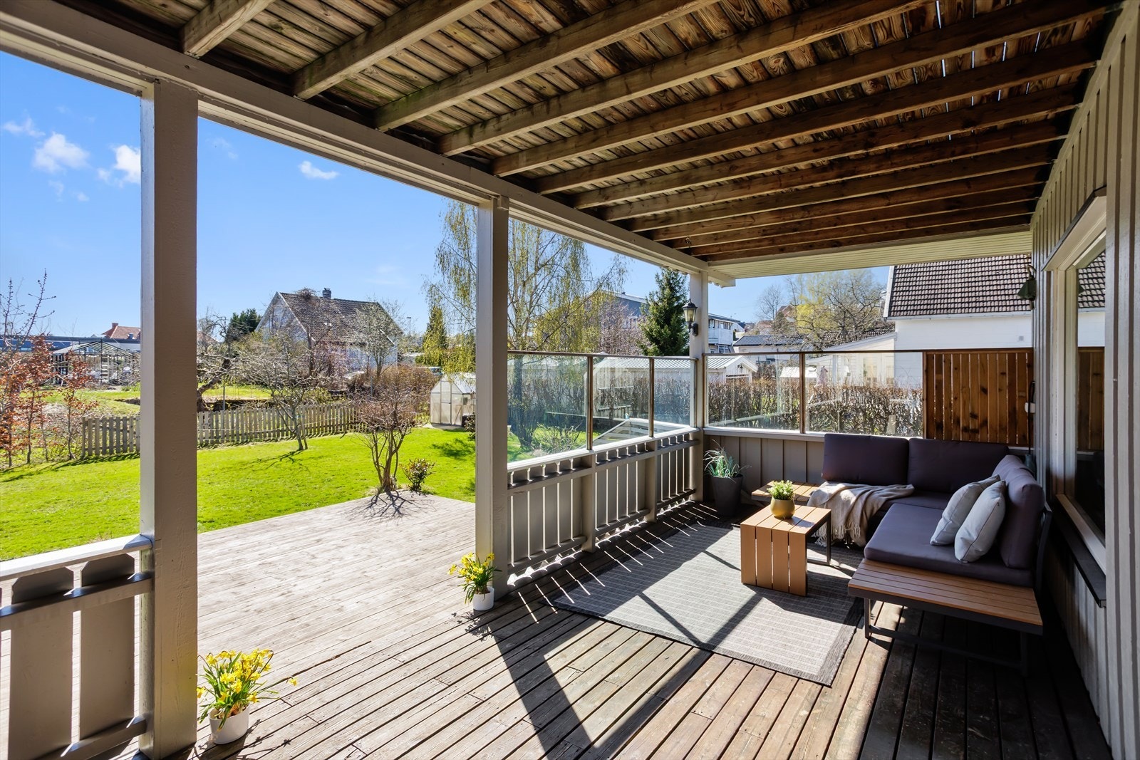 Overbygd og lun terrasse utenfor stuen i 1.etg med levegger og rekkverk som skaper en privat plass å sitte utover kvelden. Galleribilde