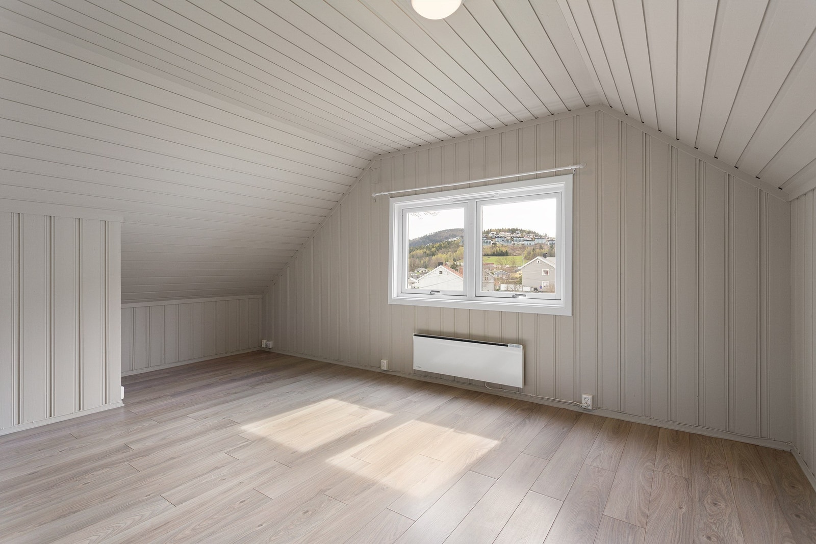 Stuen i loftsleiligheten har malt panel på vegger og i tak, med lagringsplass i kott bak knevegger. Galleribilde