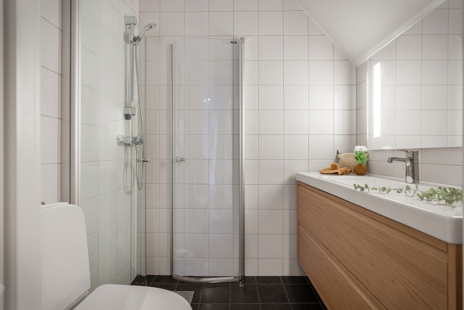 Flislagt bad med dusjhjørne, servantinnredning og wc. Galleribilde