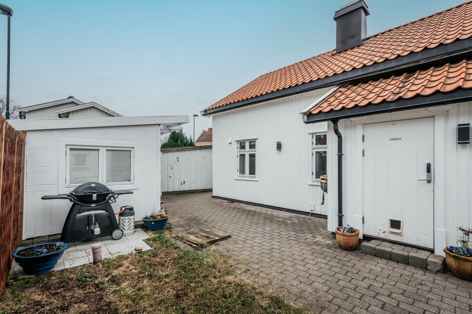 I en skjermet bakgård er det steinbelagte områder, gressplen og en lun, overbygd markterrasse på ca. 11 kvm fra 2021/2022. Galleribilde