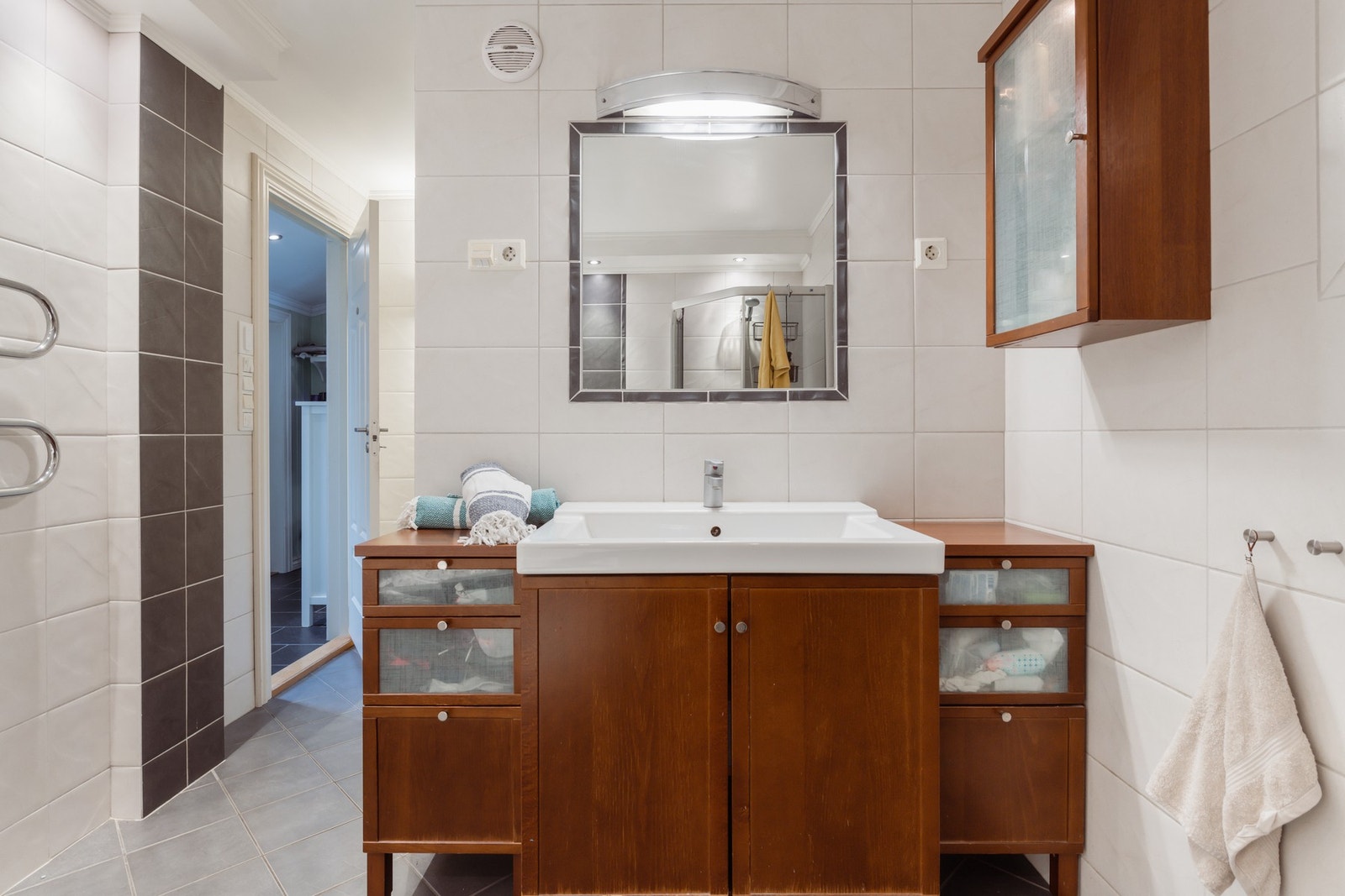 Baderomsinnredningen har gylne, glatte fronter og består av en heldekkende servant på en skapseksjon, et veggskap og et innfliset speil med belysning. Galleribilde