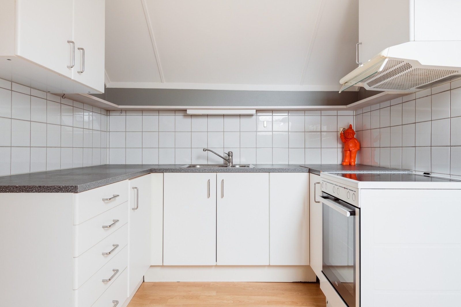 Innredningen har hvite, glatte fronter og grå laminatbenkeplate med nedfelt kum i stål. Galleribilde
