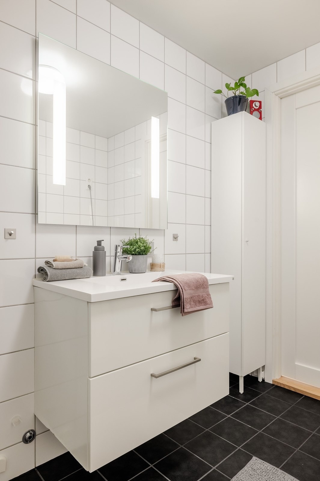 Baderomsinnredning med skuffer og heldekkende servant. Speil med lys i overkant av servanten. I tillegg er det et veggskap for ekstra oppbevaring. Galleribilde