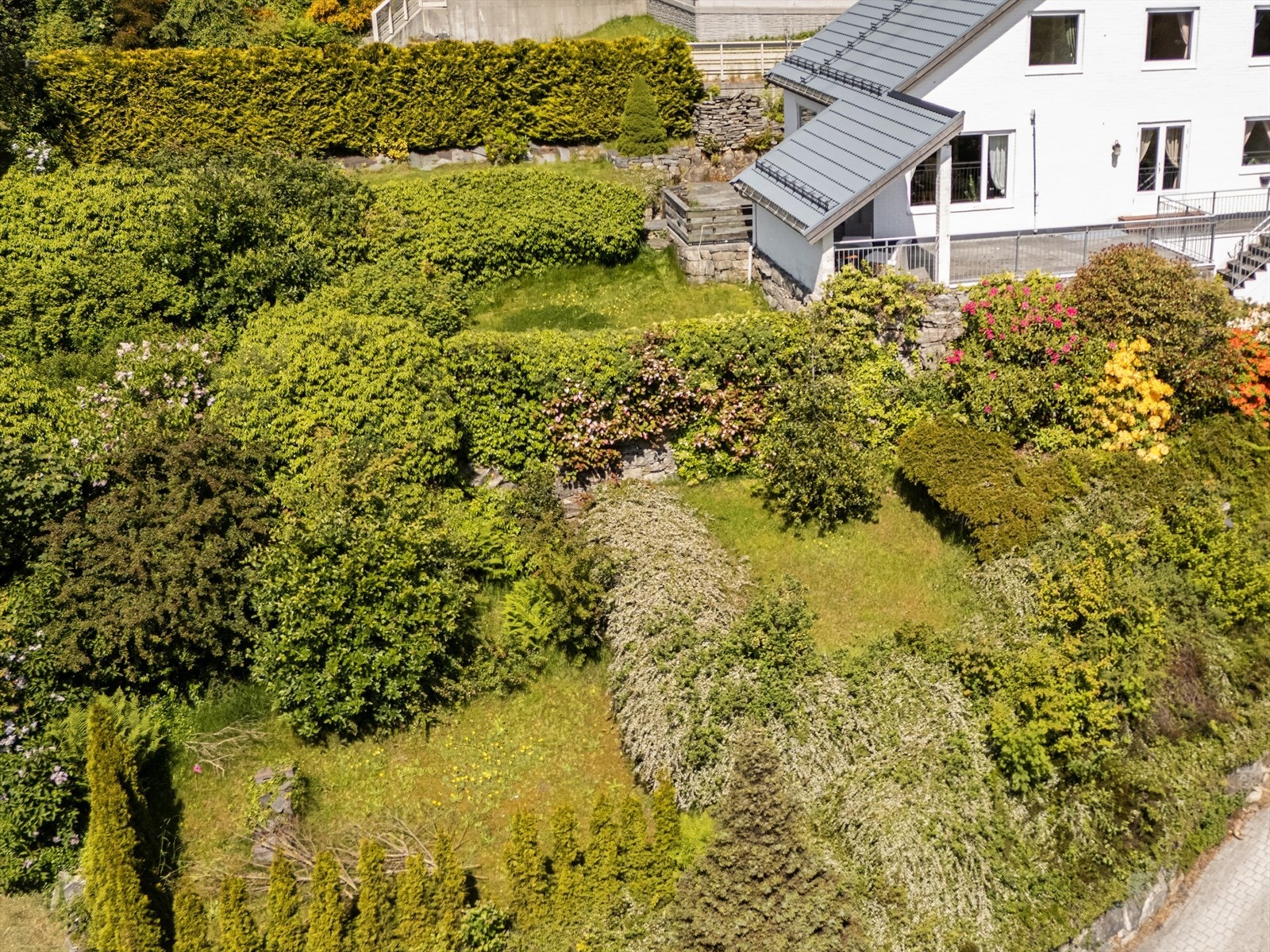 Tomten er pent opparbeidet med flere nivåer og beplantning med ulike buskevekster. Galleribilde